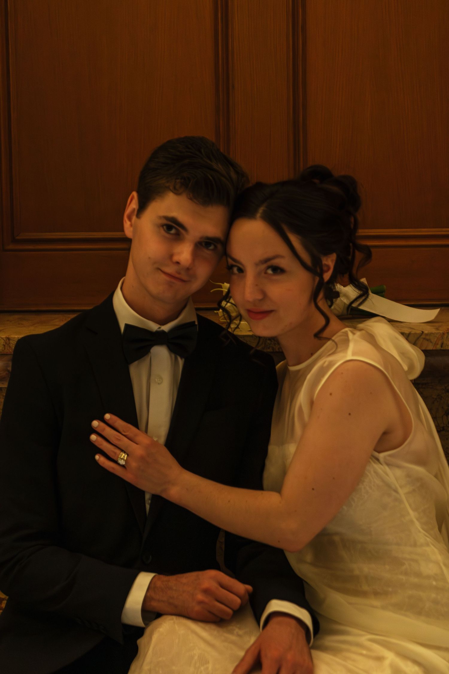 A couple in wedding attire sharing tender moments against wood paneled walls.