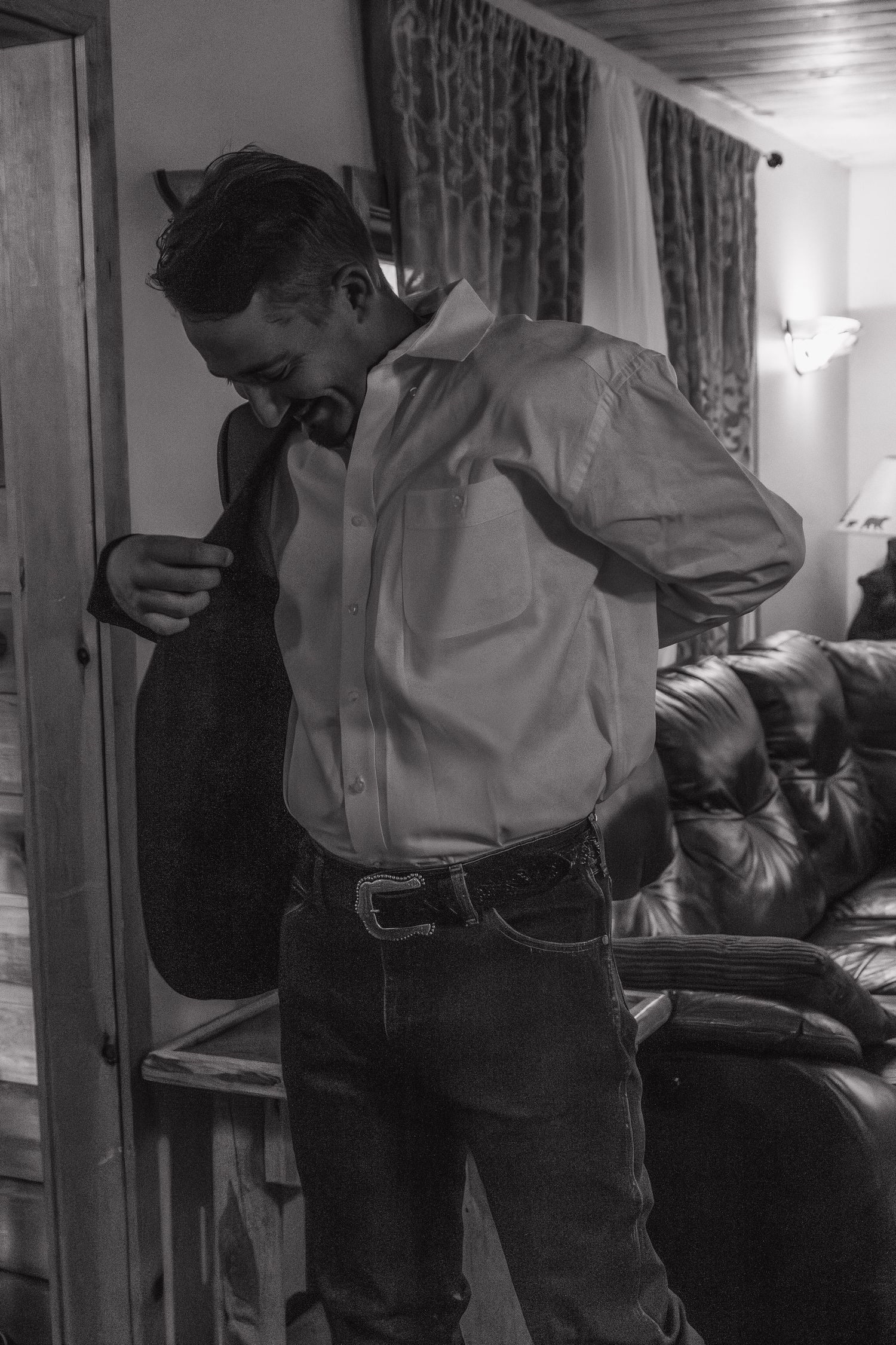 Black and white photo of someone getting dressed in formal western attire.