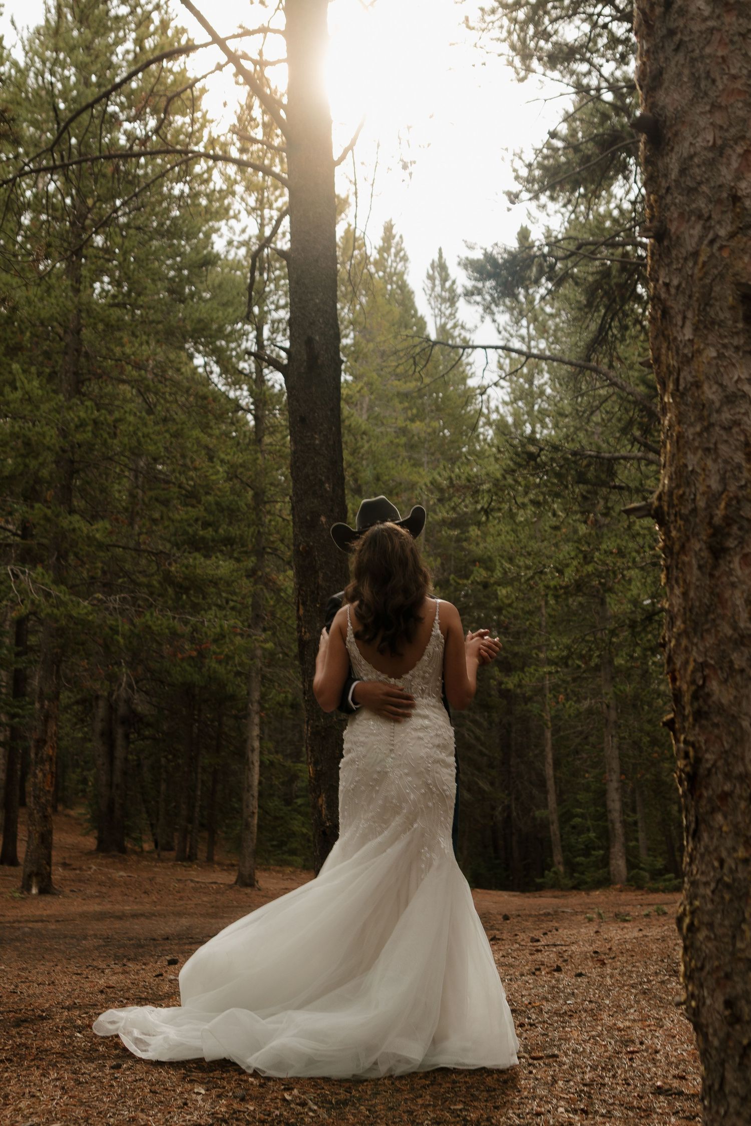 A bride in a flowing white gown twirls through a serene forest setting.