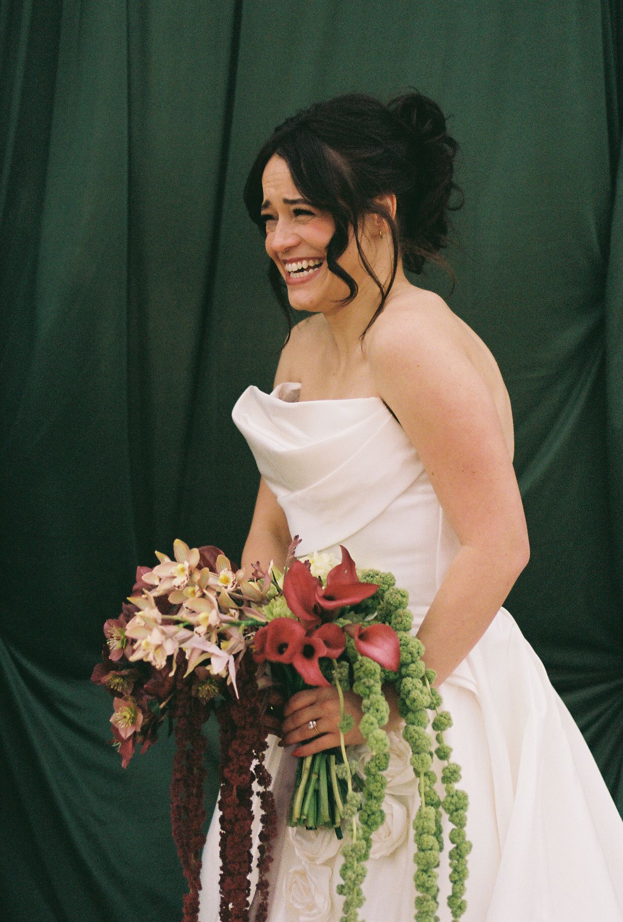 A bride holding a stunning cascading bouquet with pink flowers and greenery.