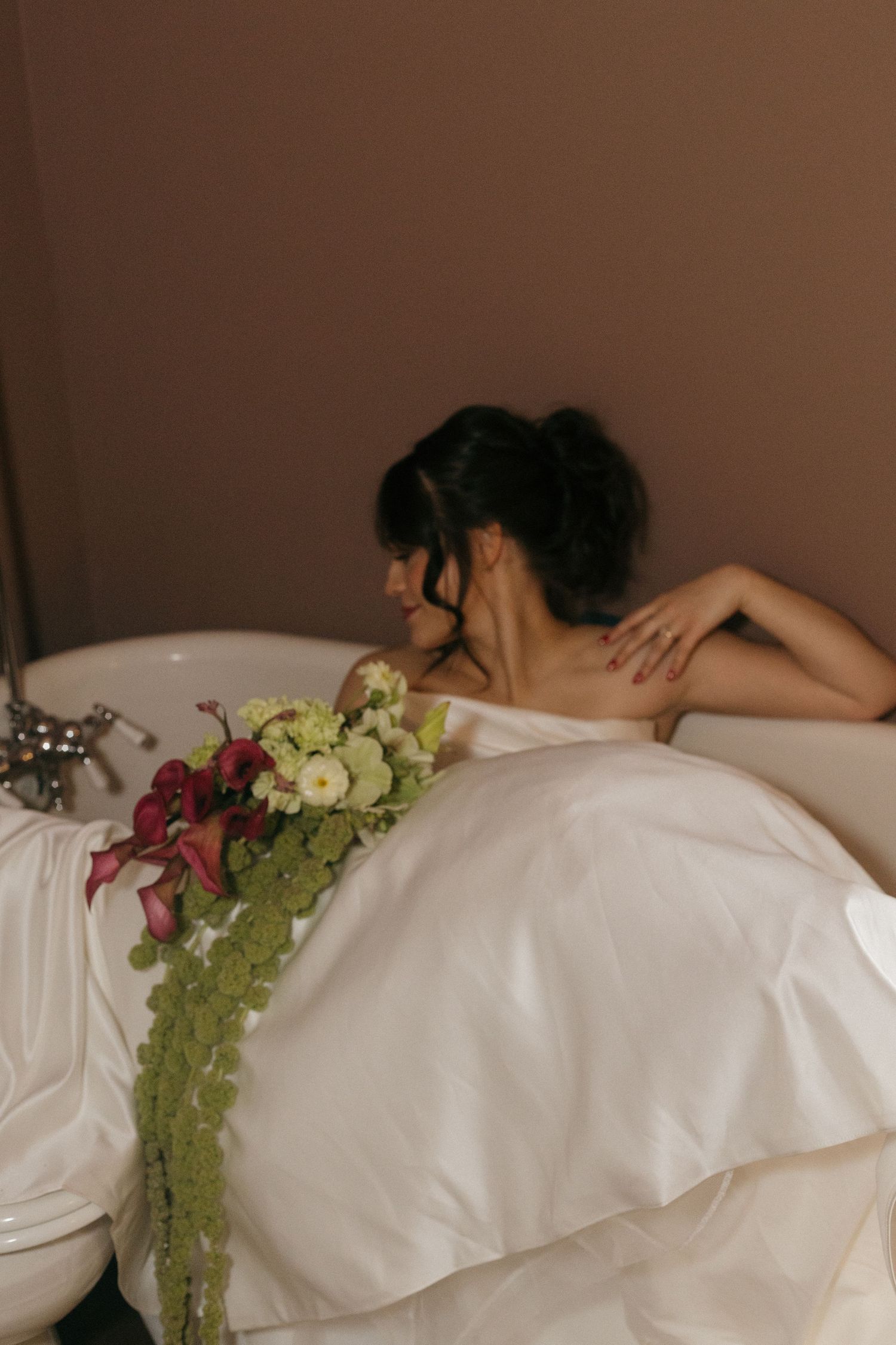 White wedding dress draped on a bed with colorful floral accents.