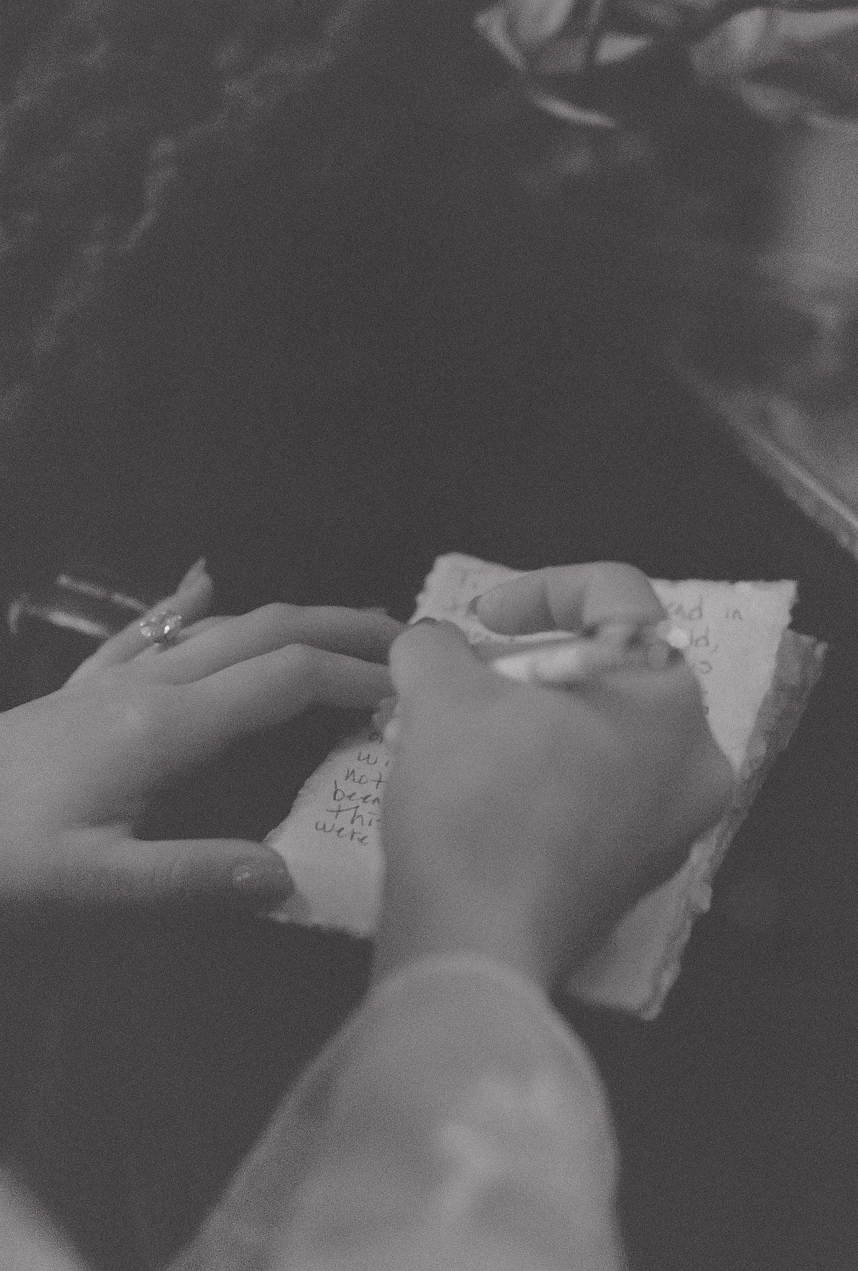 Hands writing in a journal captured in black and white photography.