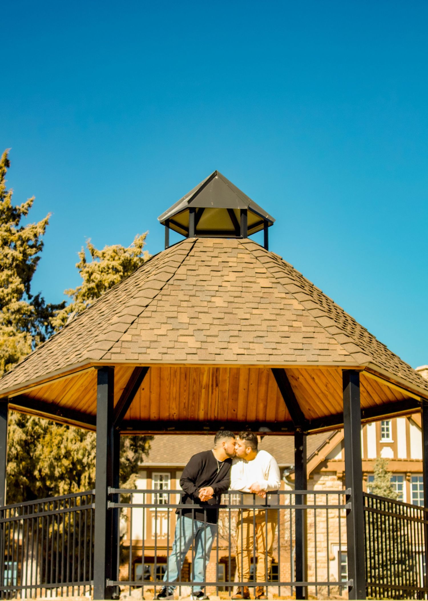 Wooden gazebo structure with ornate roof details against vivid blue sky.