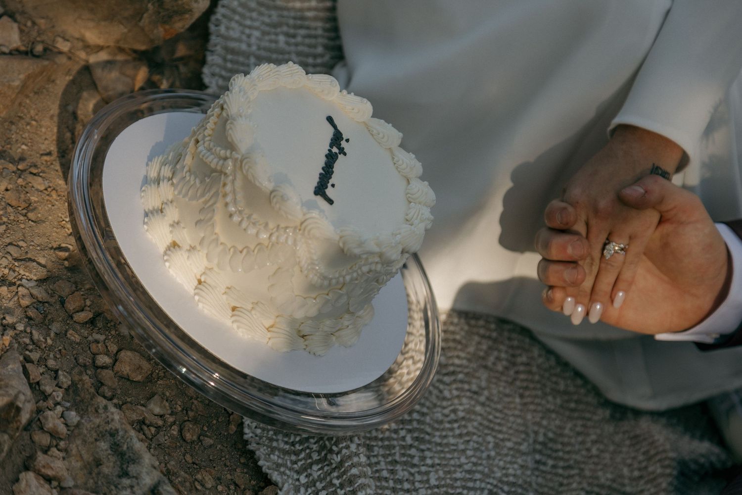 Couple cutting a small white ruffled wedding cake on a silver tray during an outdoor mountain elopement ceremony.