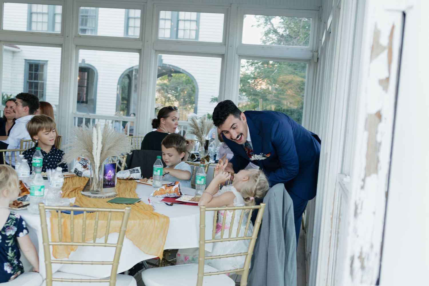 Wedding reception scene with guests dining at decorated tables.