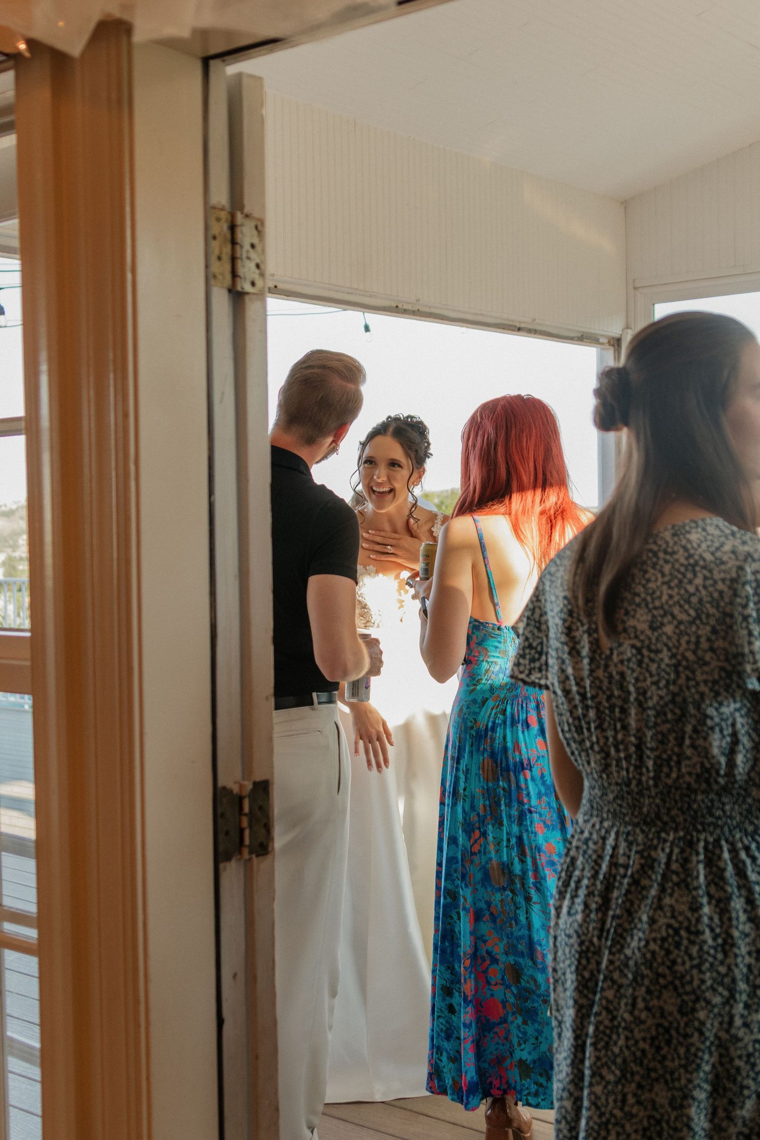 Group of women in colorful dresses gathered indoors during wedding preparations.