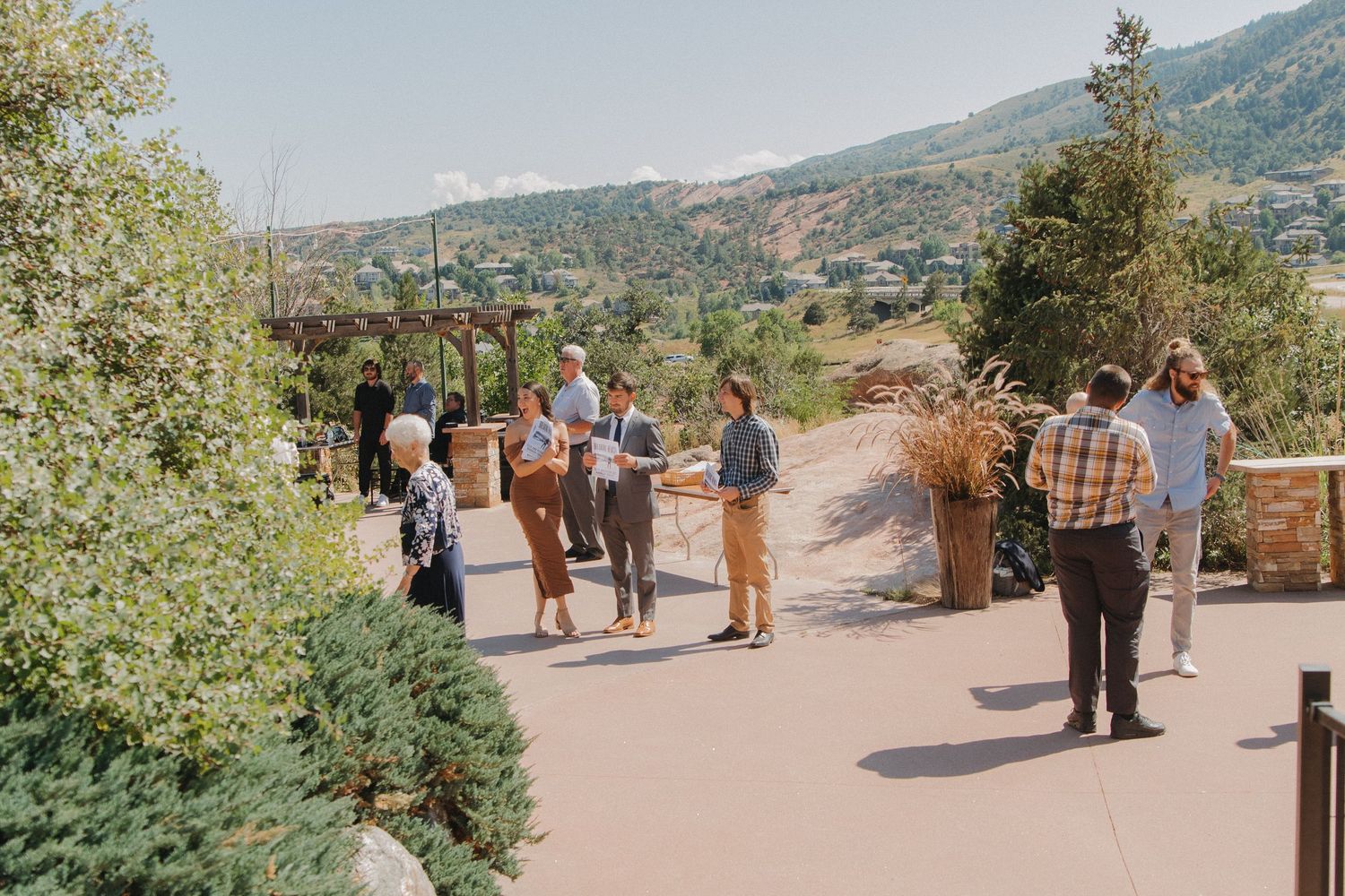 Beautiful mountain landscape setting with outdoor wedding setup and guests.