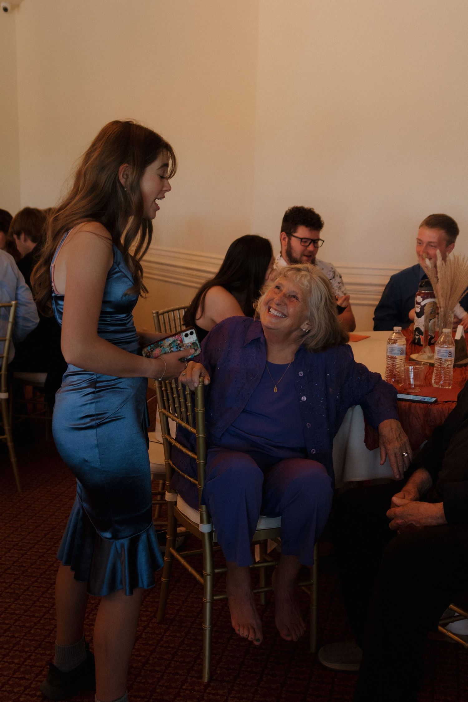 Wedding guests mingling and laughing at reception tables.