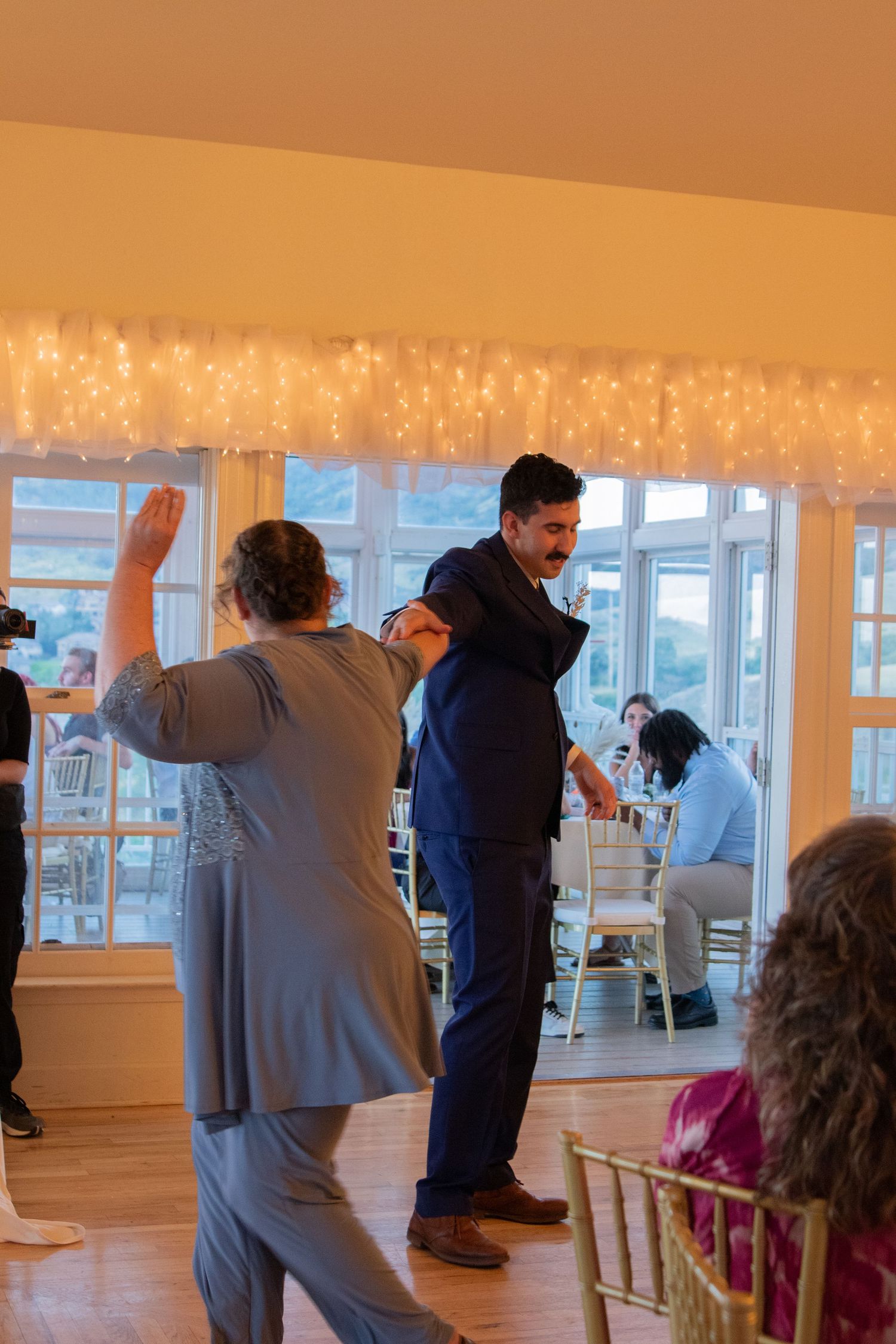 Wedding guests dancing and celebrating in a beautifully lit reception venue.