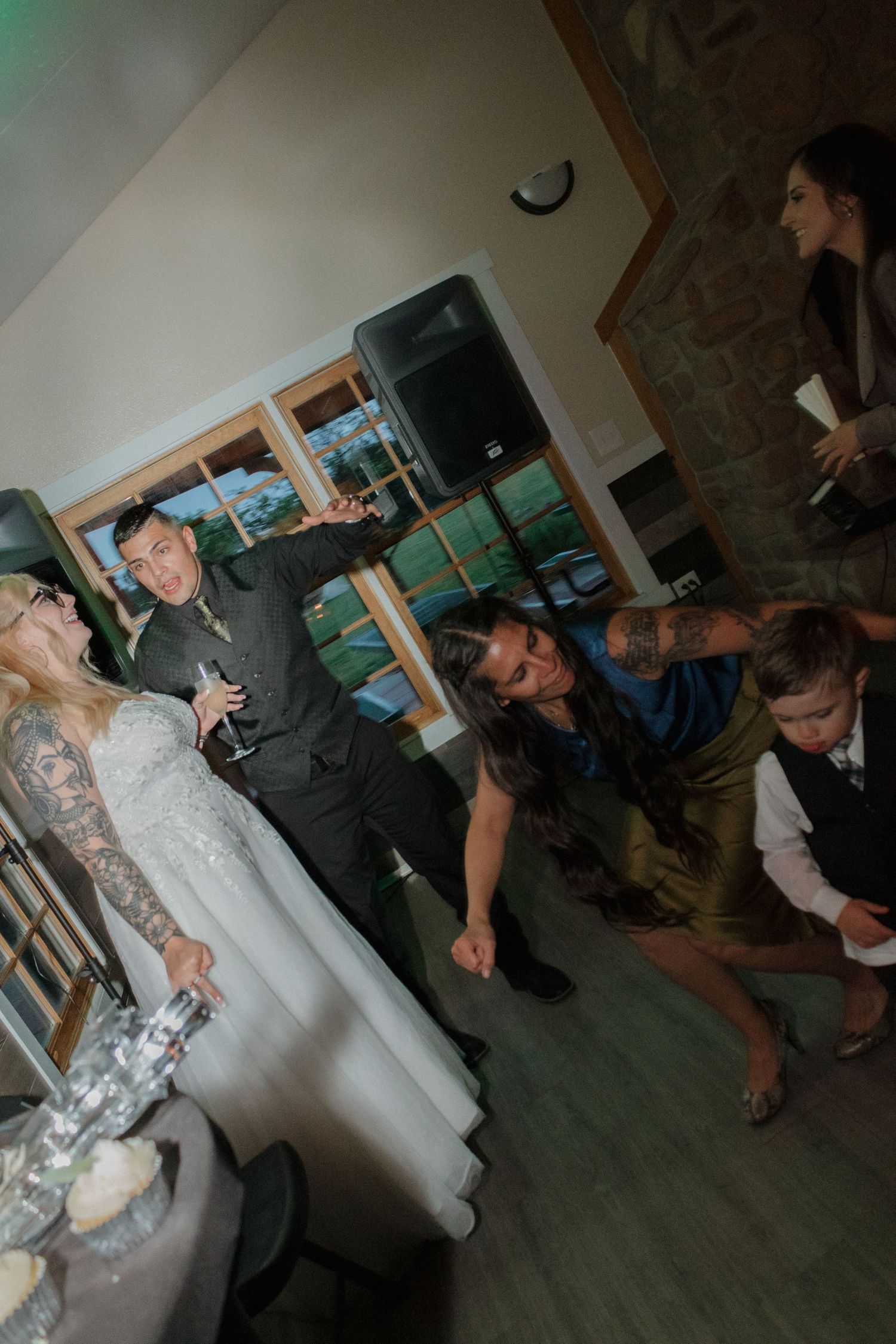 People dancing and moving across a dark hardwood floor at a wedding reception.