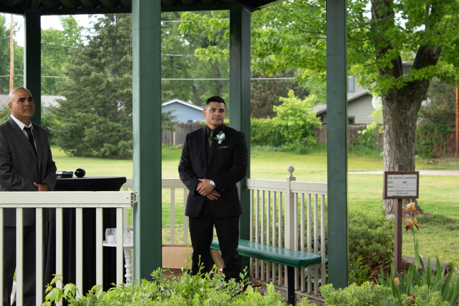 Wedding party members gathered under covered outdoor pavilion.