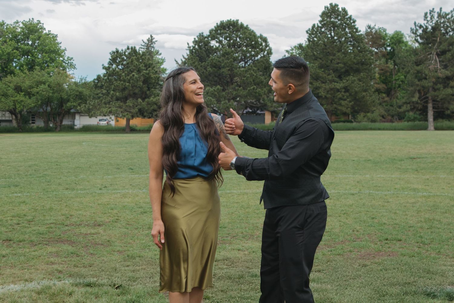 Wedding party members share playful interactions in an outdoor field setting.