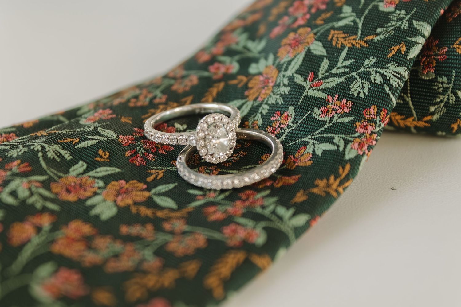 Diamond engagement and wedding rings set against a floral vintage fabric pattern.
