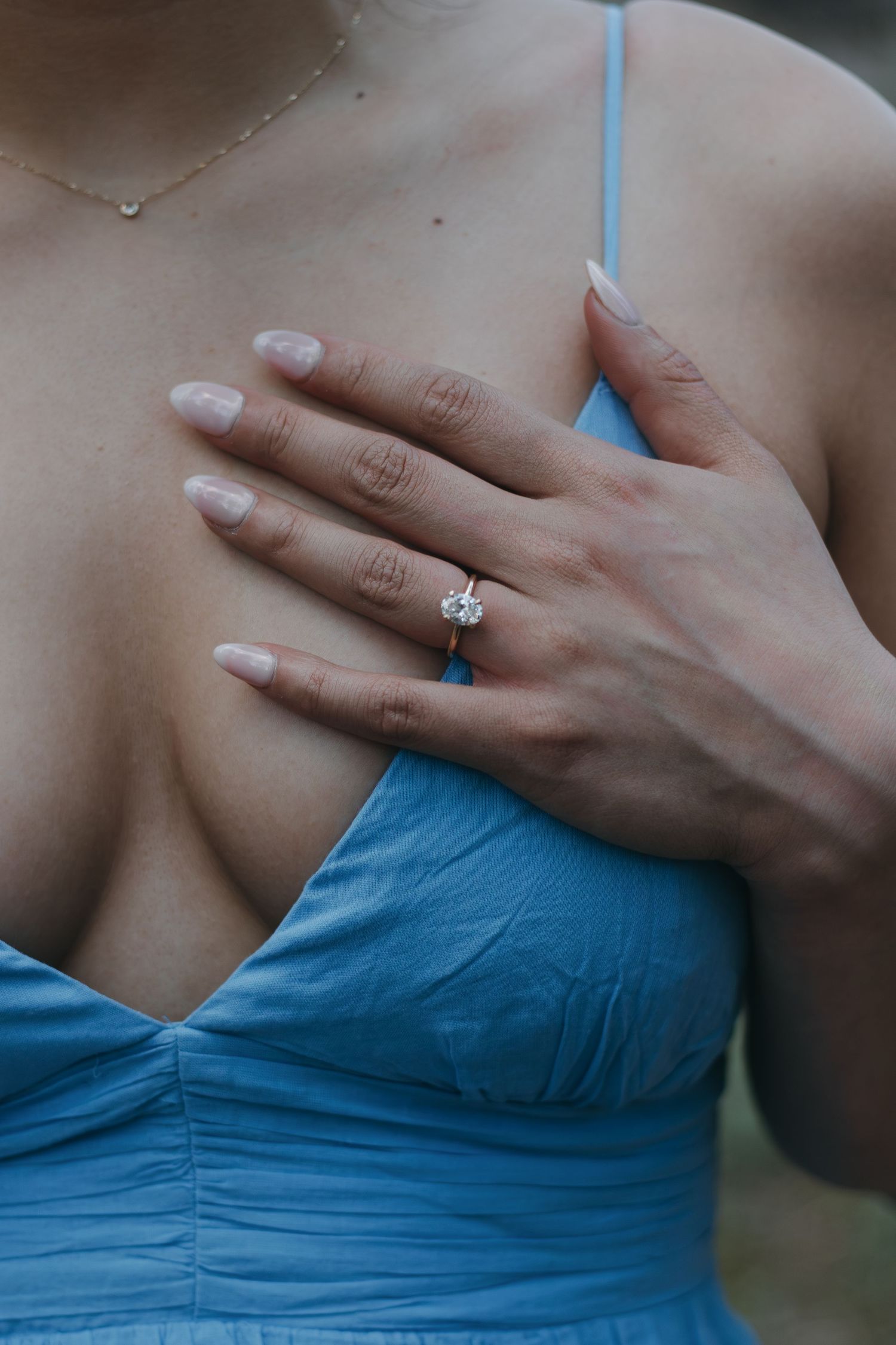 Close-up of hands with engagement ring against a light blue dress bodice.