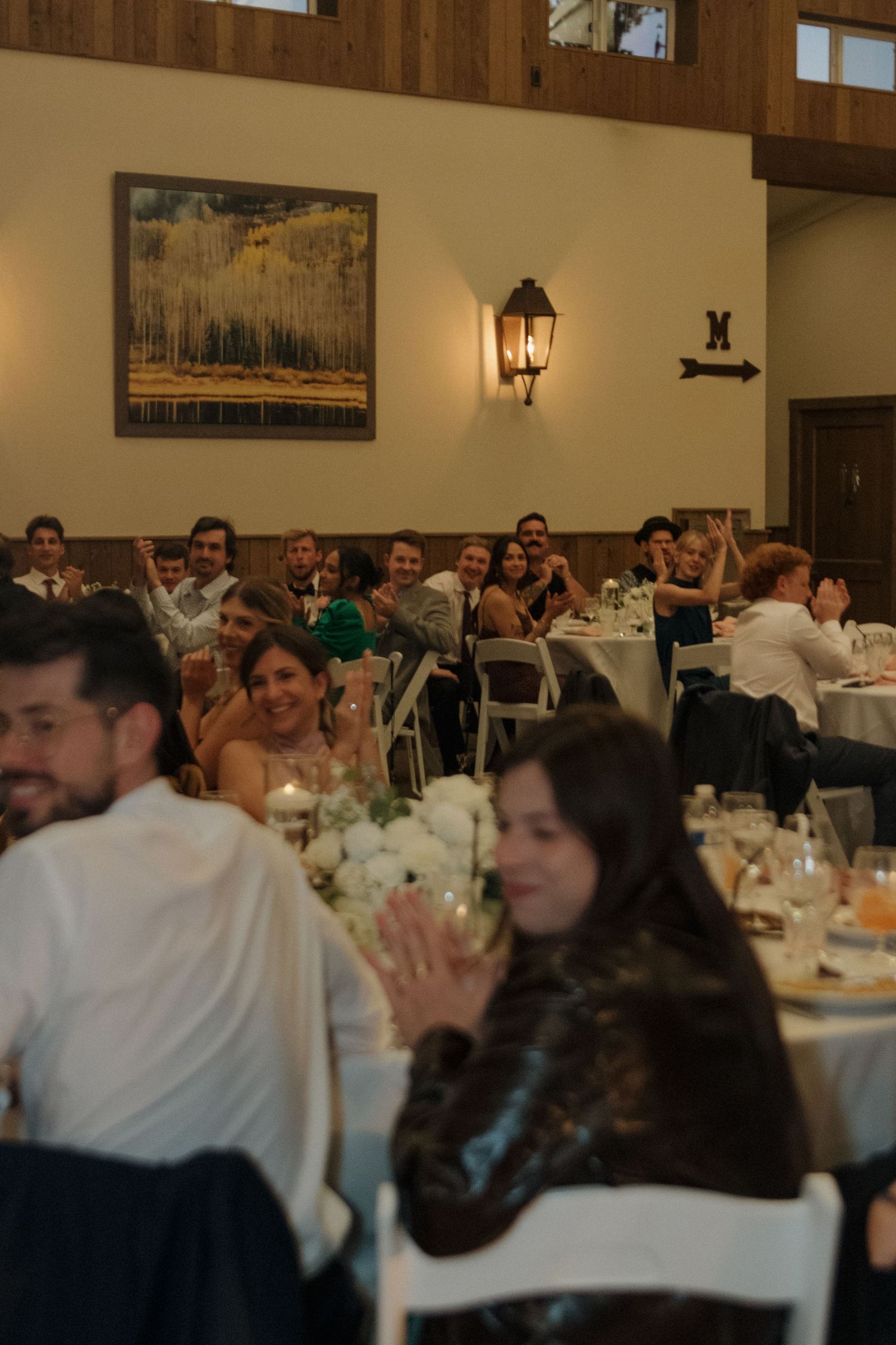 Wedding reception in a rustic wooden venue with tables set for dining.