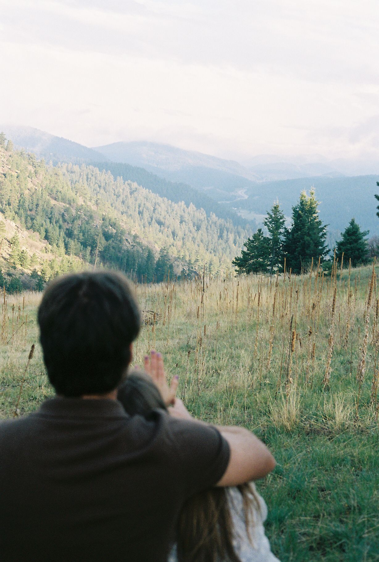Couple sitting together overlooking scenic mountain valley and forest landscape.