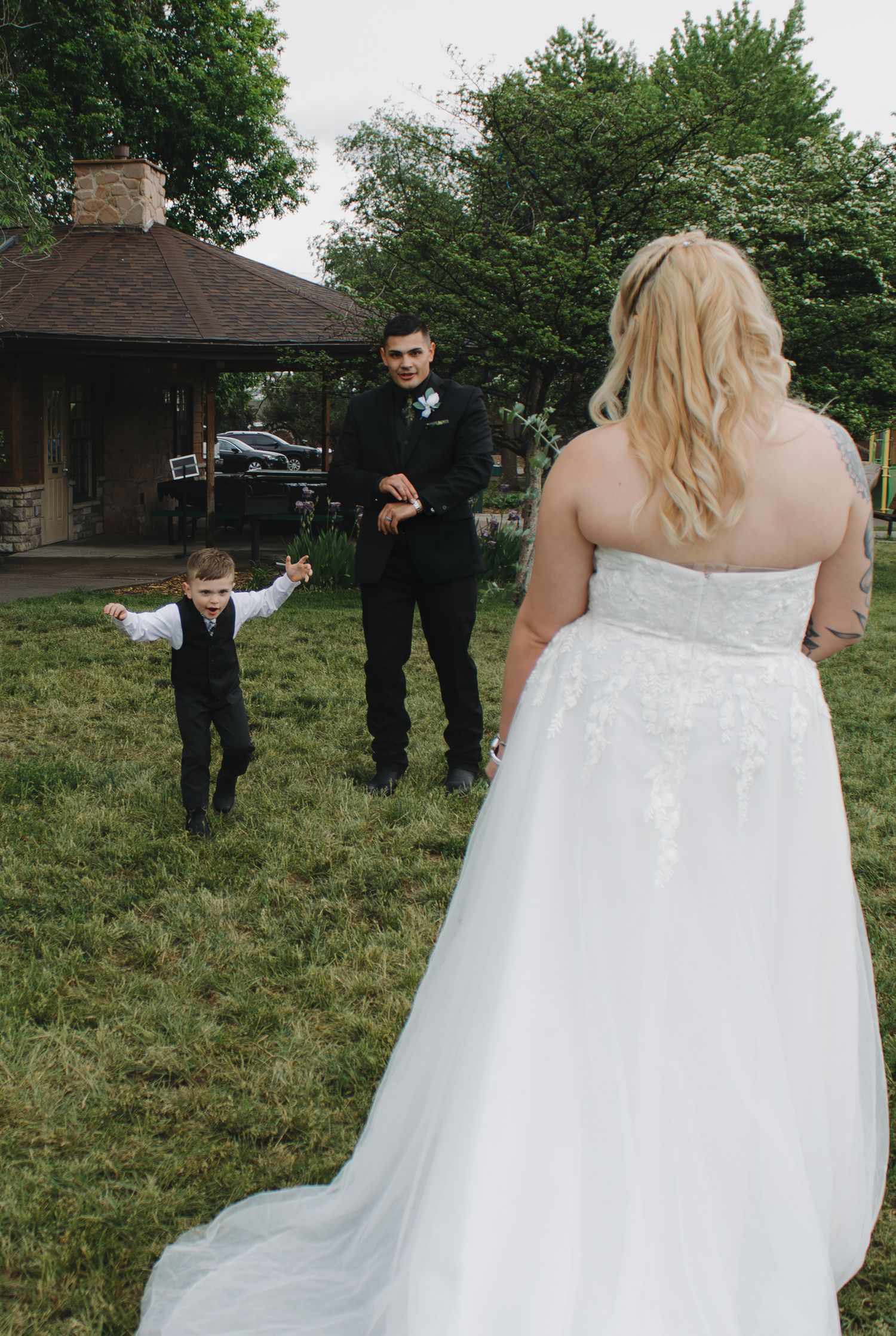 A wedding dress flowing in the breeze during an outdoor ceremony with a gazebo in the background.