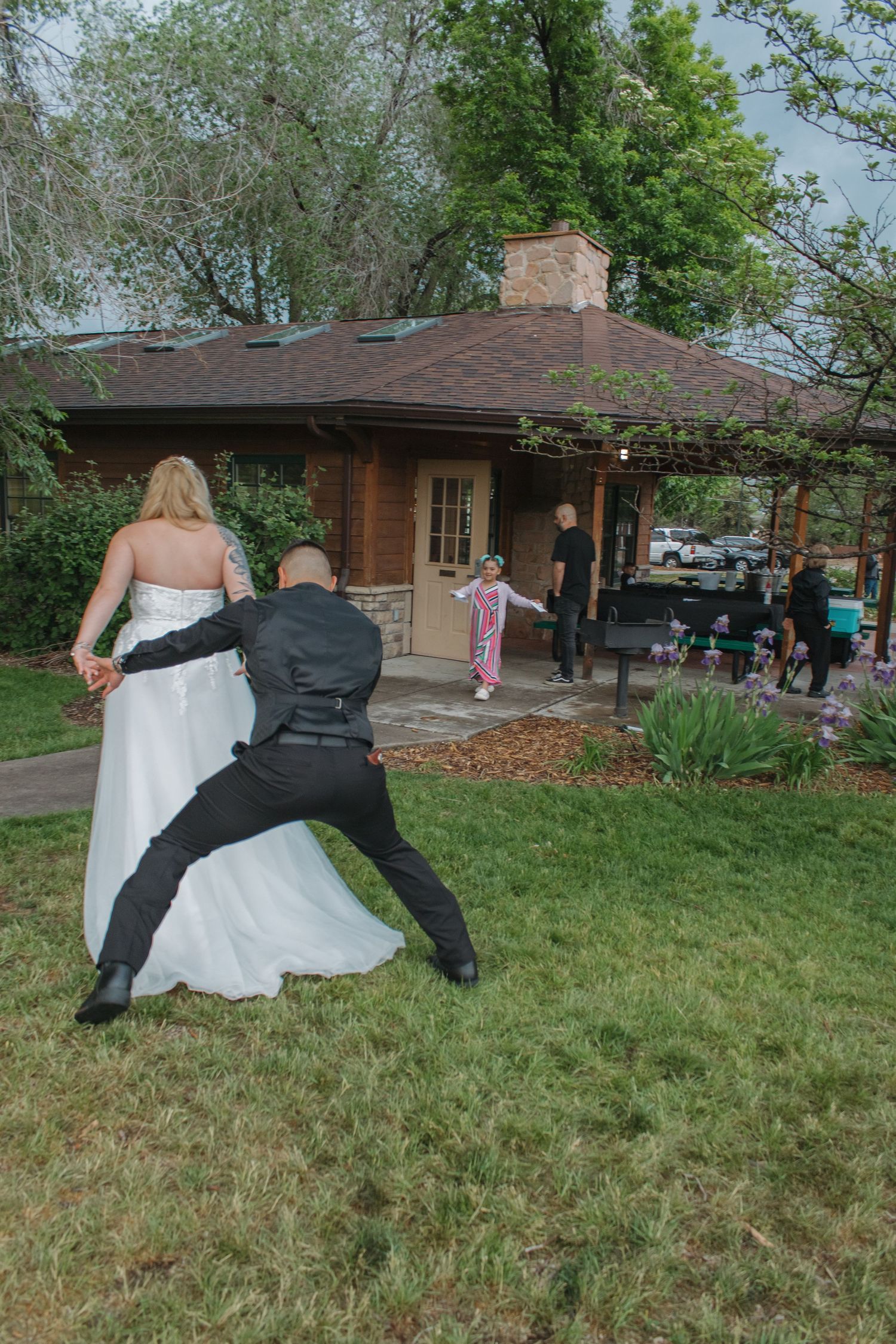 Wedding couple playfully falling on grass during outdoor photo session.