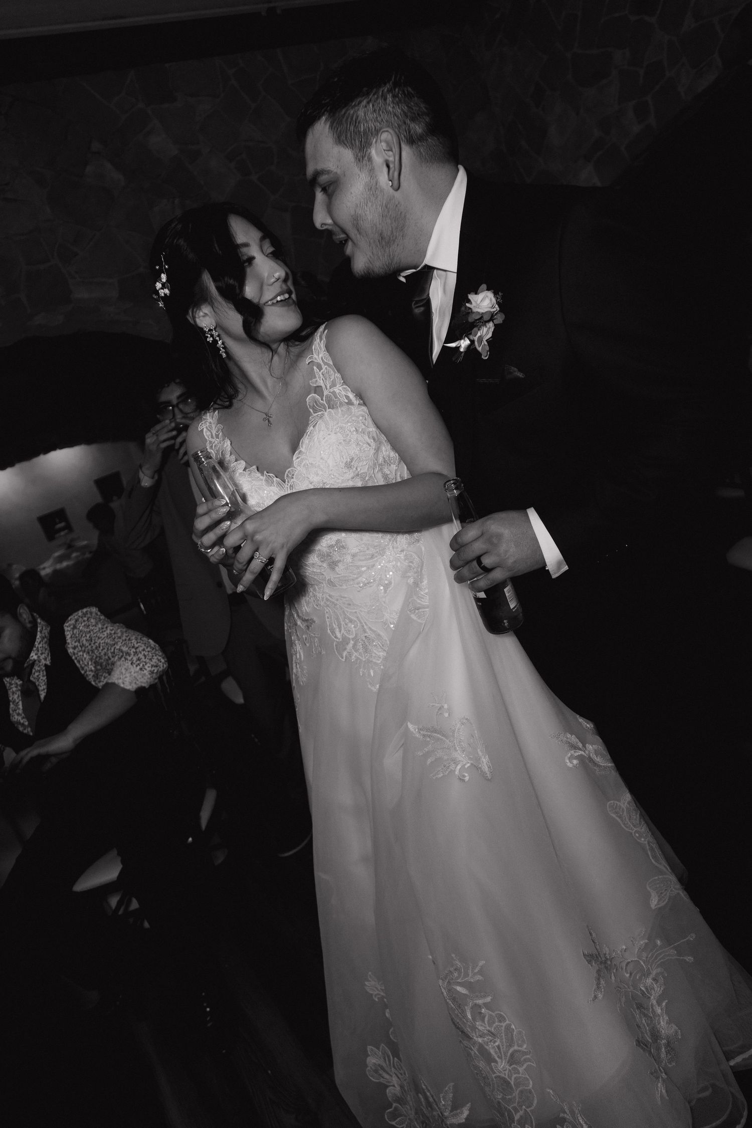 Black and white photo of smiling bride and groom dancing closely together at their wedding reception.
