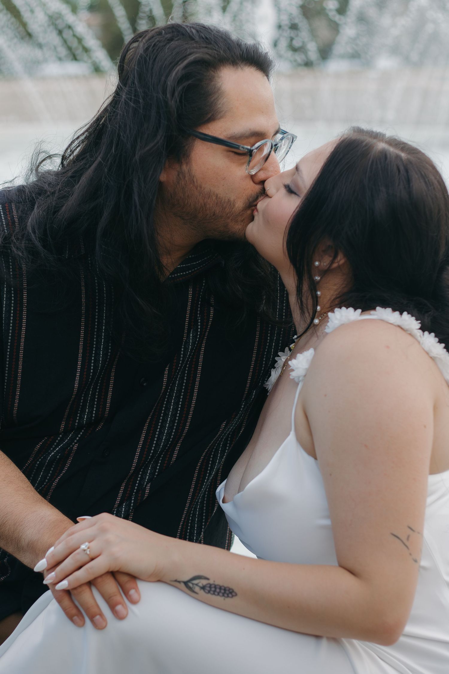 An intimate moment captured between a couple in black and white attire against a misty background.