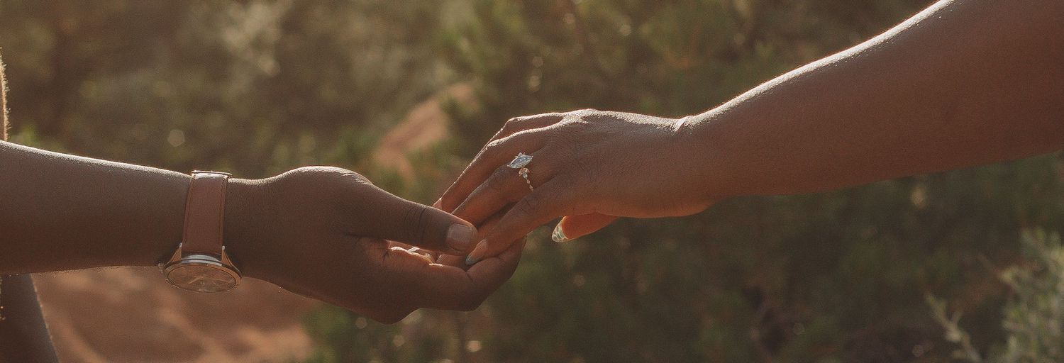 Two hands reaching out to hold each other in warm sunset lighting.