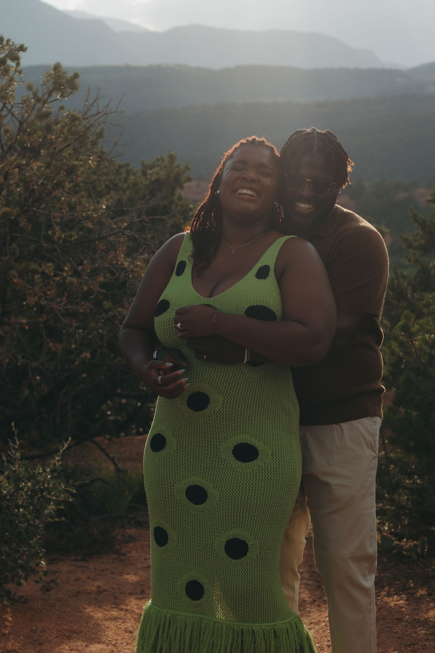 A romantic embrace captured against a misty mountain landscape at sunset.