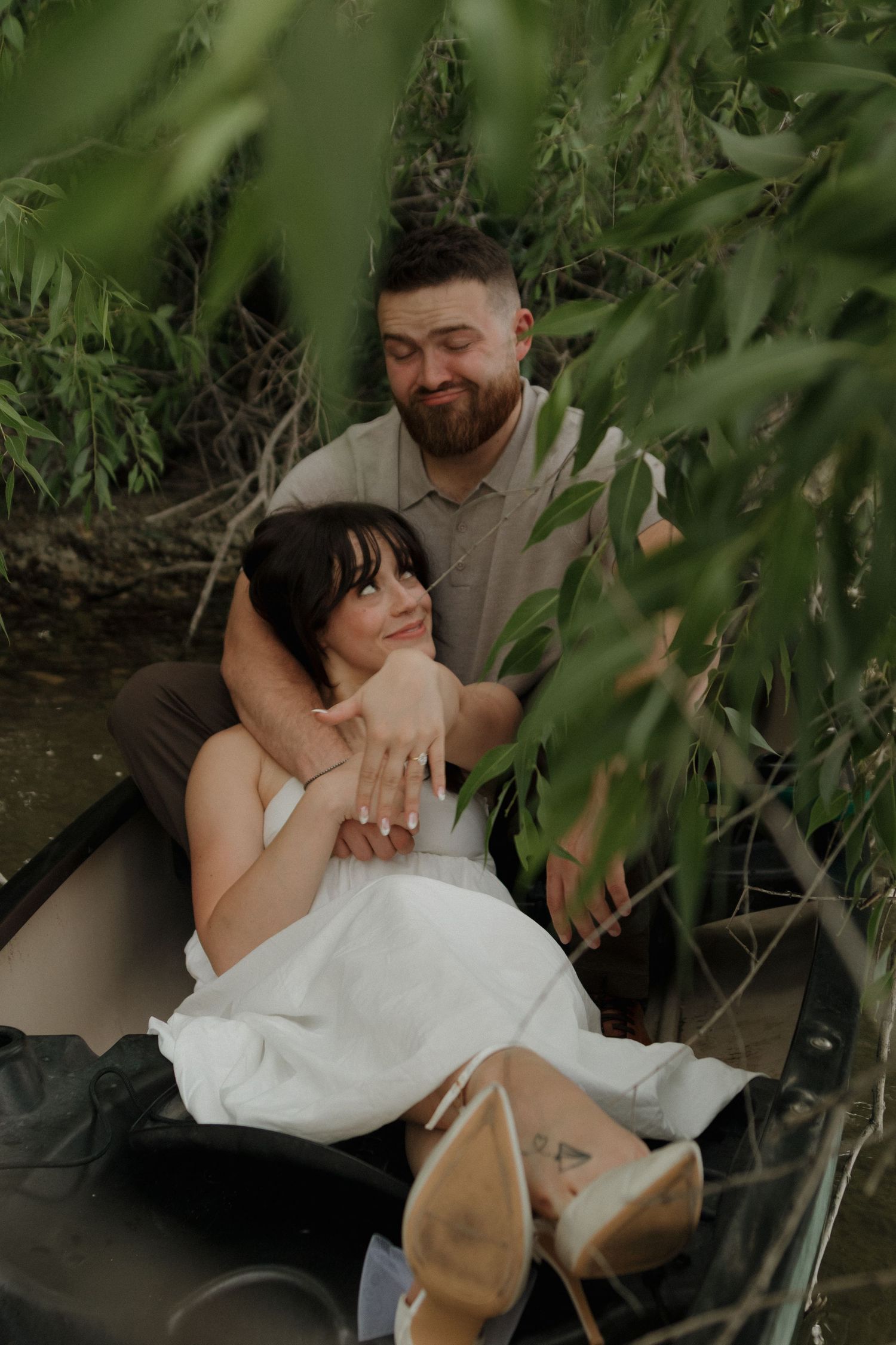 Couple shares intimate moments in a boat against a natural backdrop.