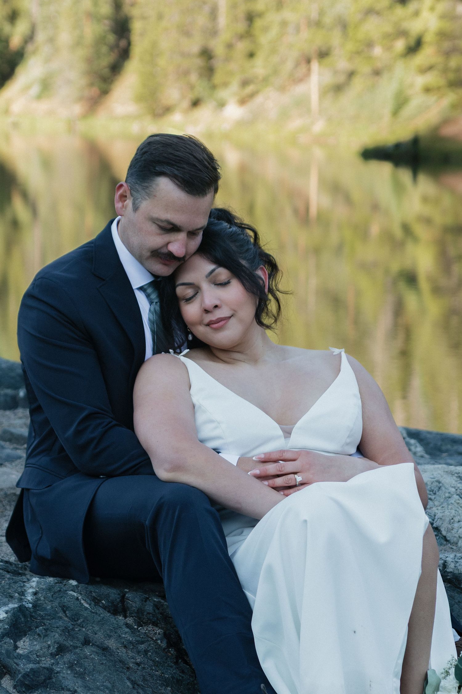 A romantic lakeside moment between newlyweds against a mountain backdrop.
