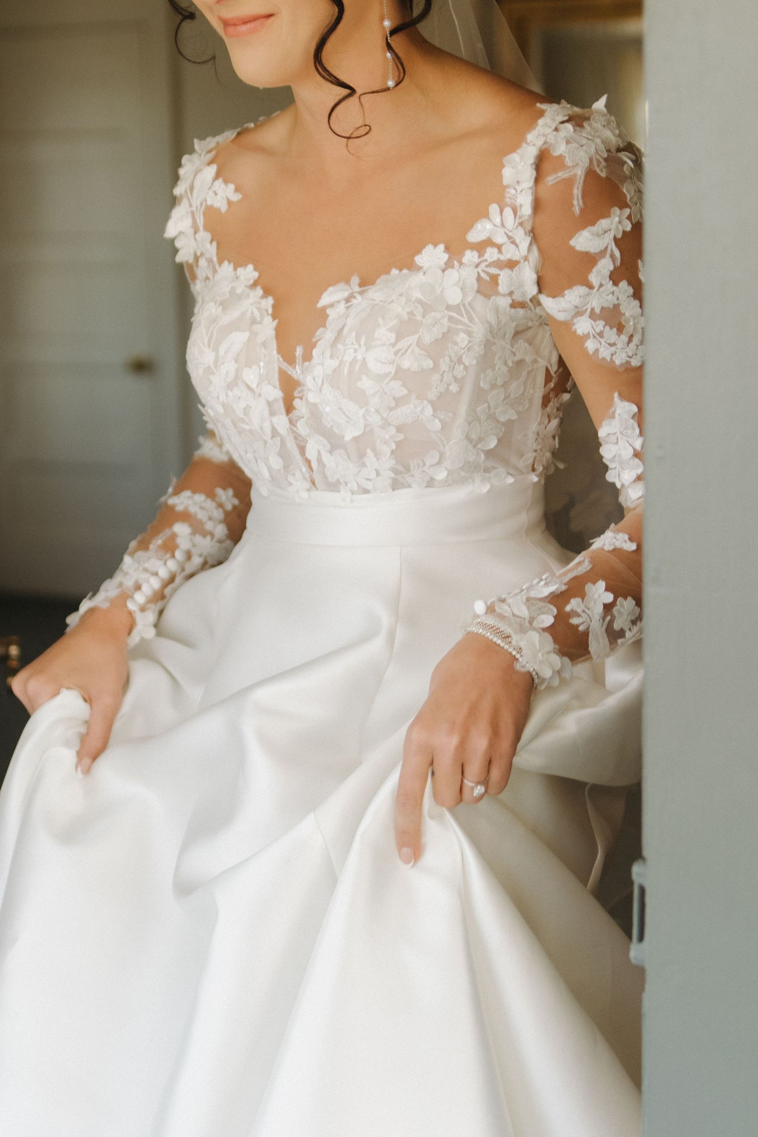 Close-up details of a white wedding dress with delicate lace and floral appliques.