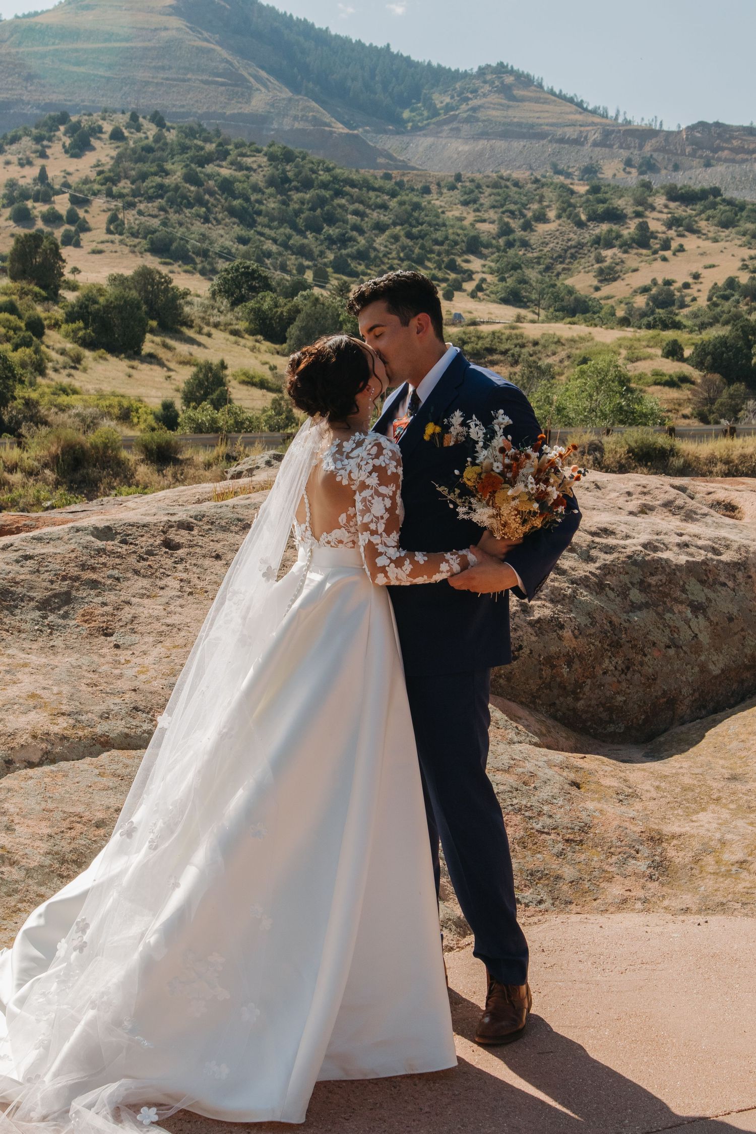 A romantic wedding photo shoot on a scenic mountain overlook with red rock formations.