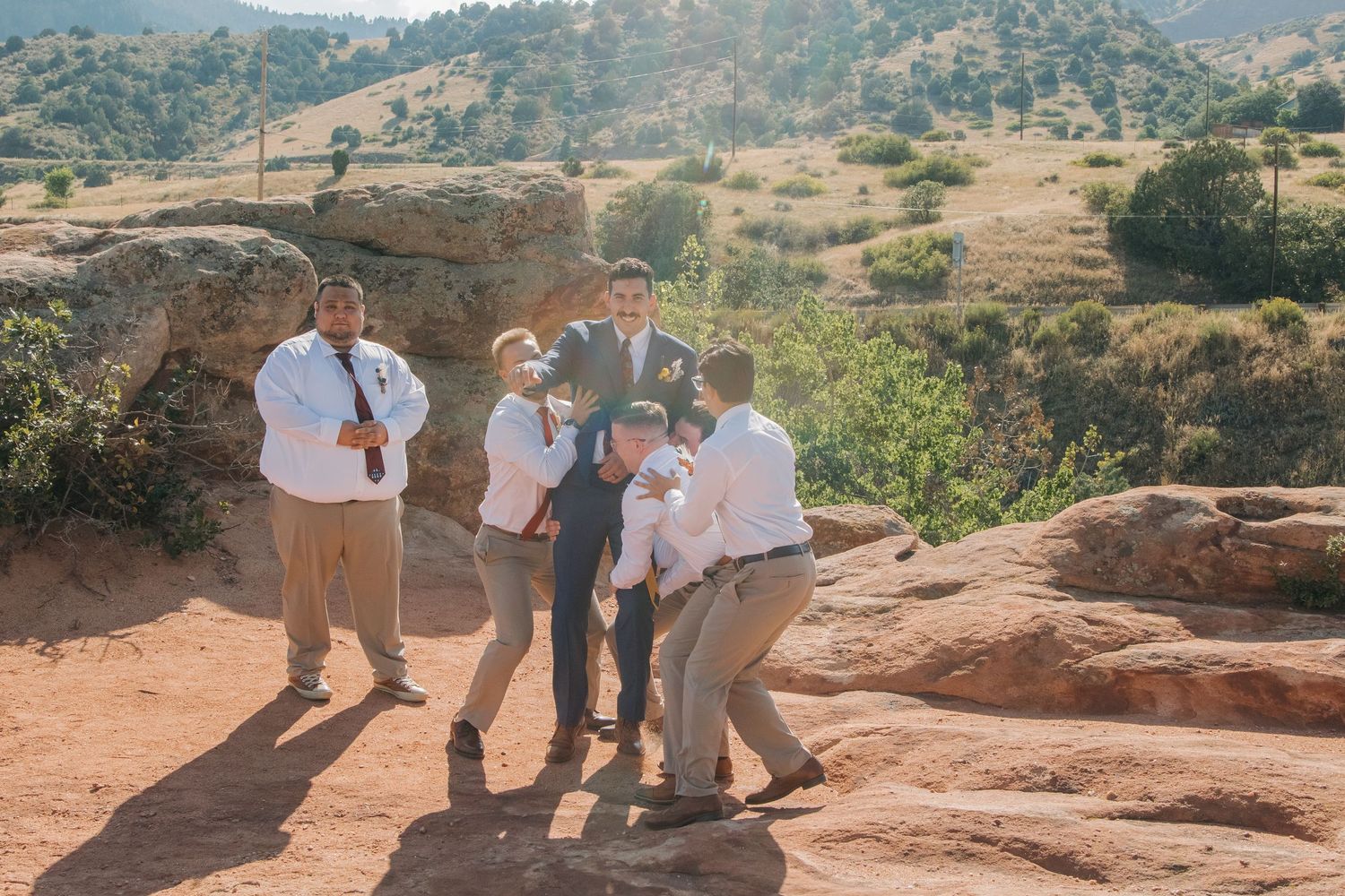 Wedding party poses on red rocks during an outdoor desert ceremony.