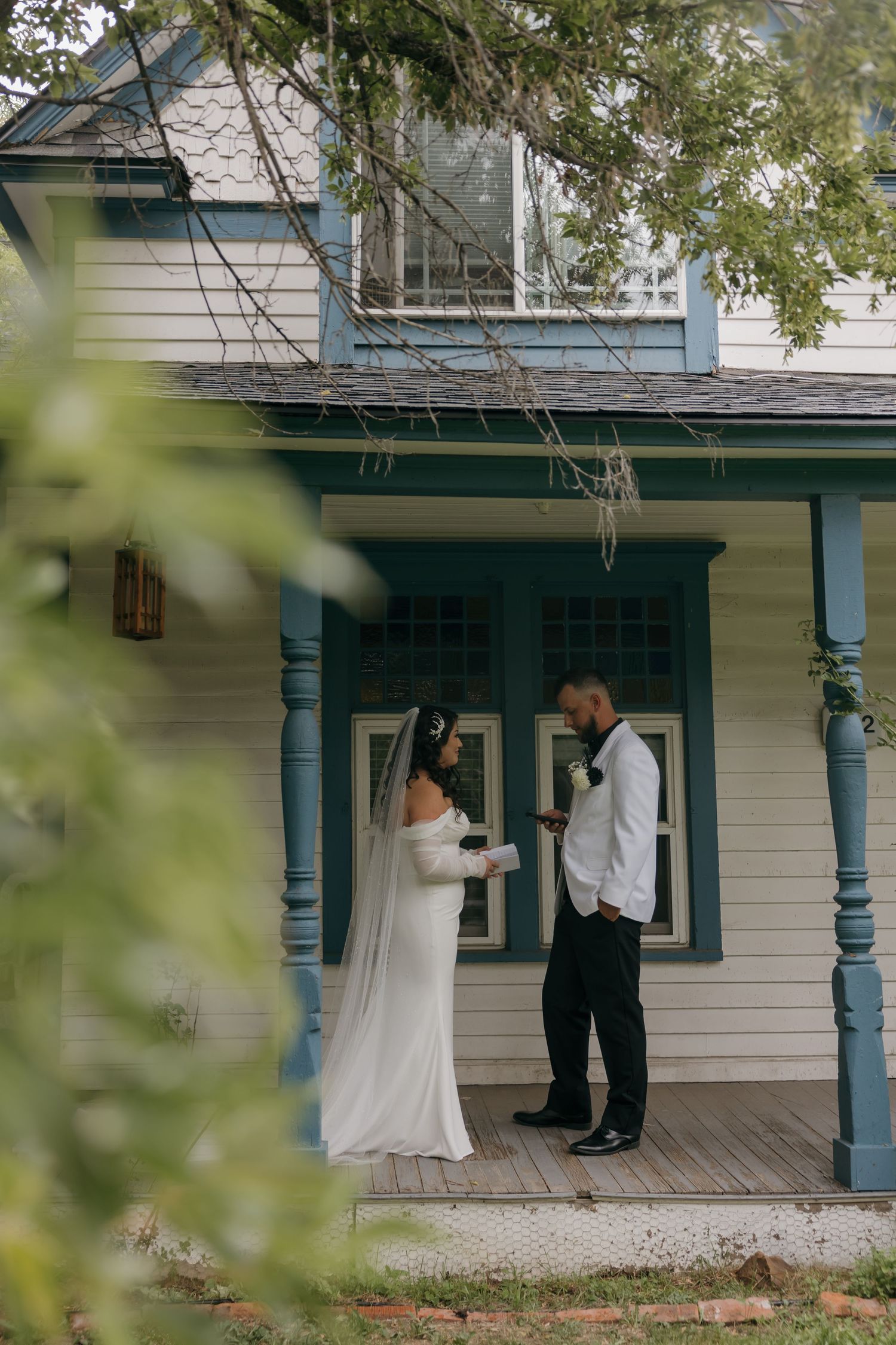 Bride and groom exchanging vows on a charming blue and white Victorian porch on their wedding day.