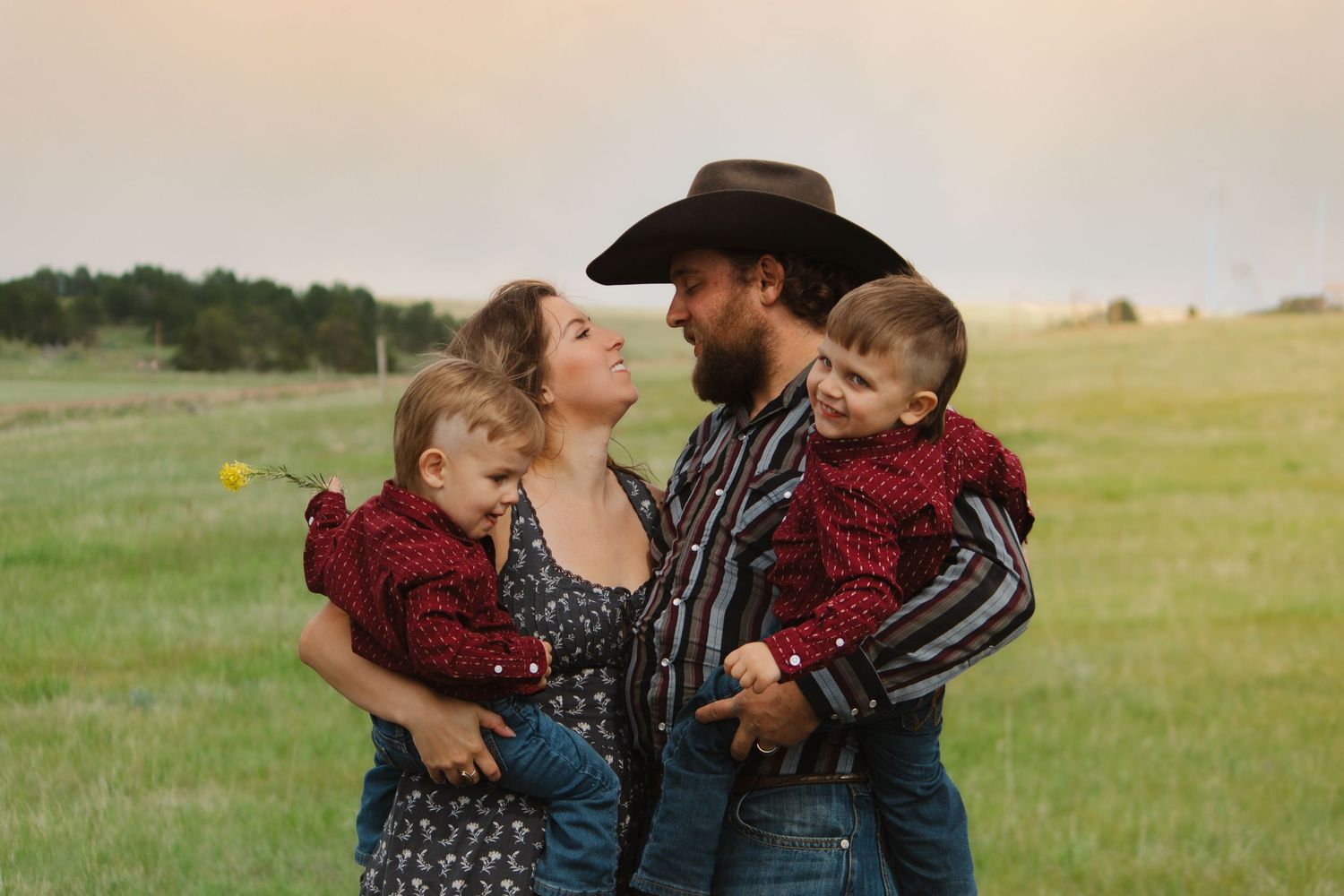 Intimate family moment captured outdoors in country setting at golden hour.