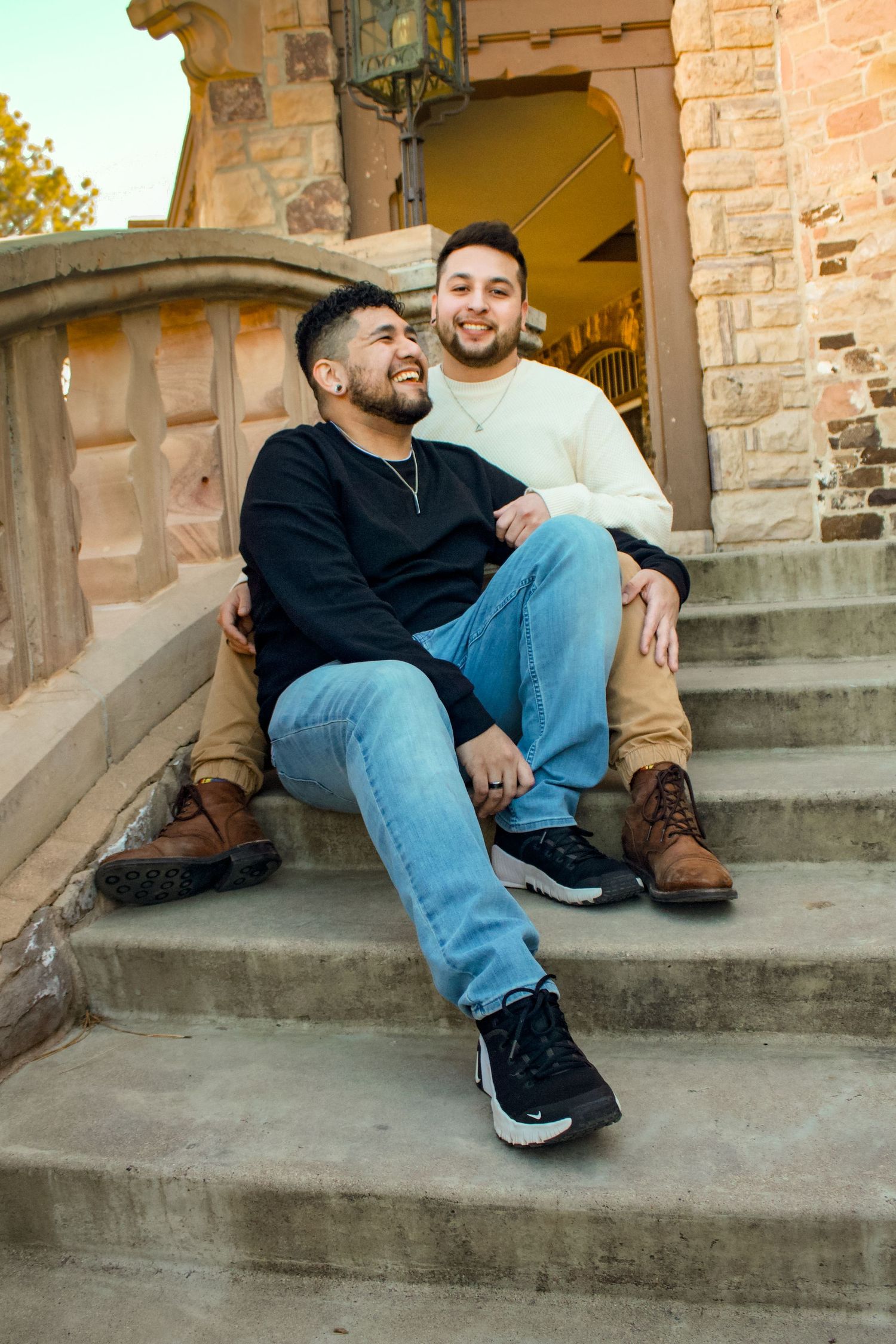 A couple sitting and laughing together on stone steps outside a historic building.