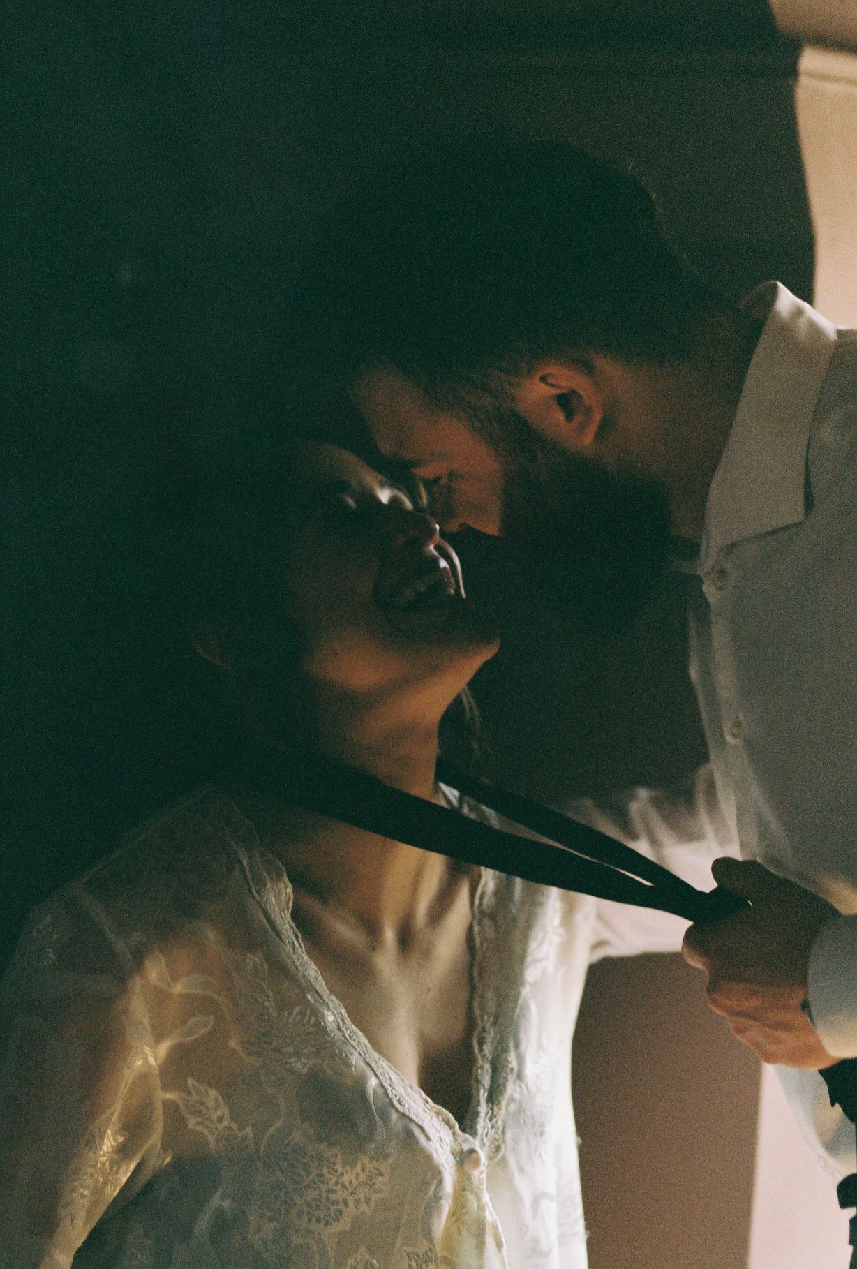 An intimate wedding moment captured in moody, artistic lighting.