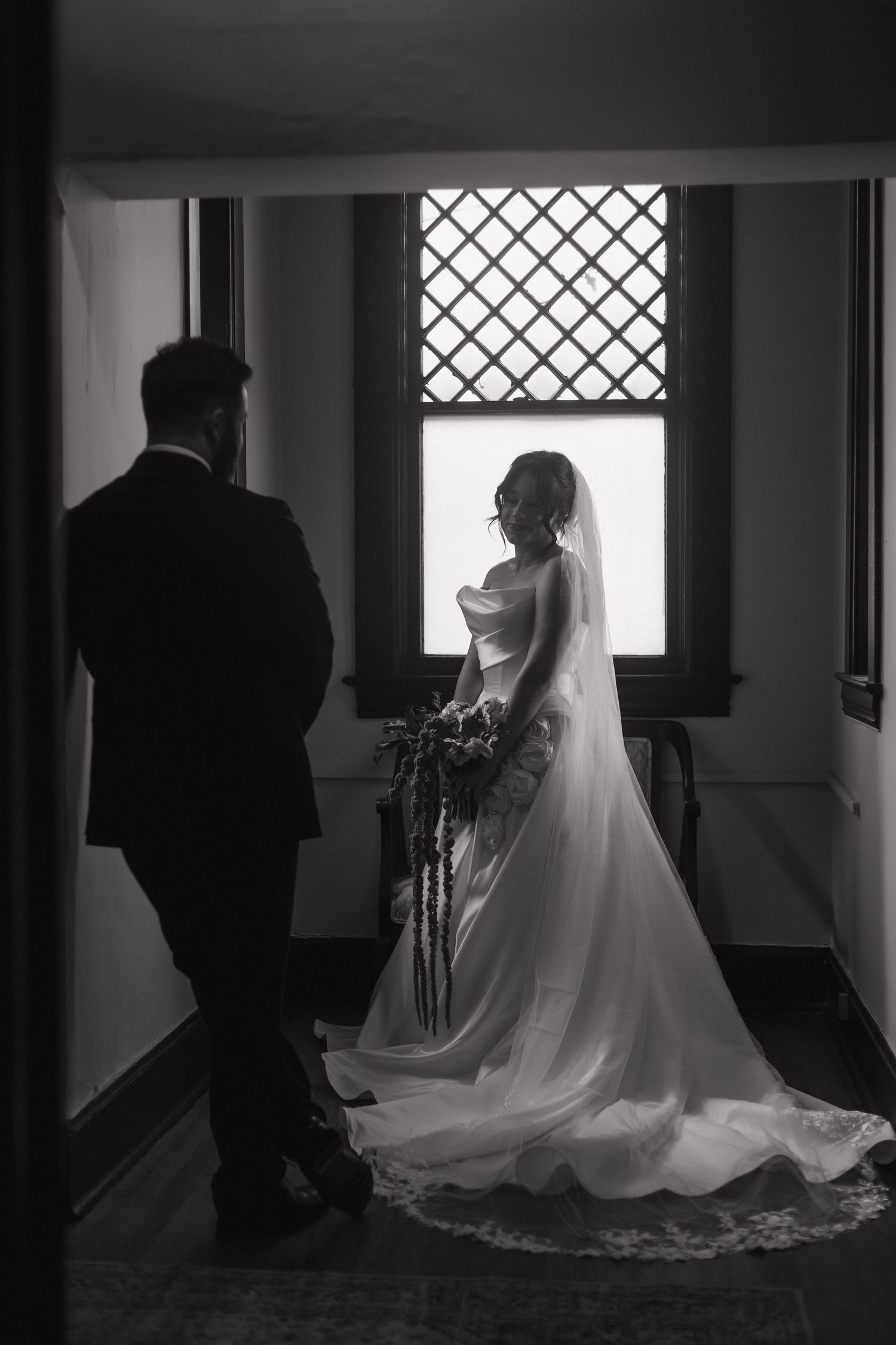 Dramatic black and white hallway scene with a flowing white wedding dress train.