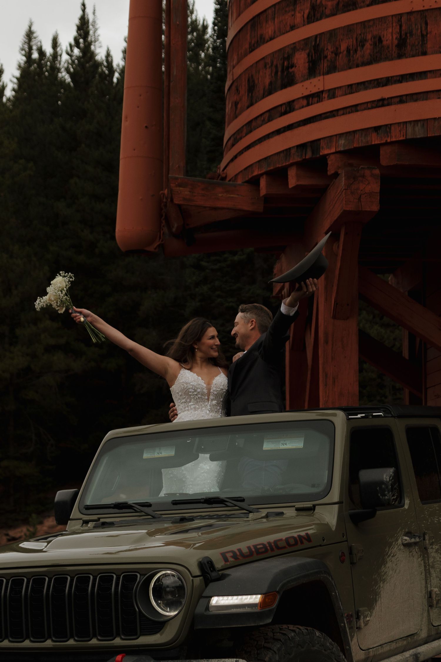 A joyful celebration moment on top of a Jeep Rubicon with rustic backdrop.