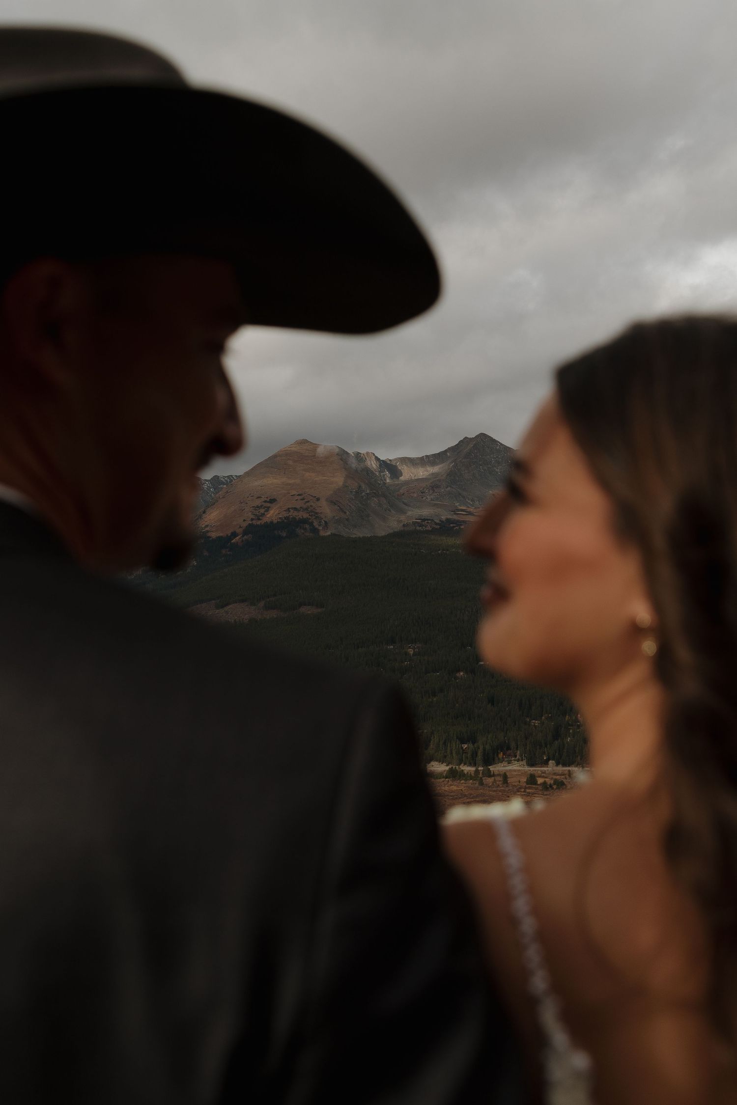 A dramatic wedding photoshoot against a mountain backdrop with moody storm clouds in the background.