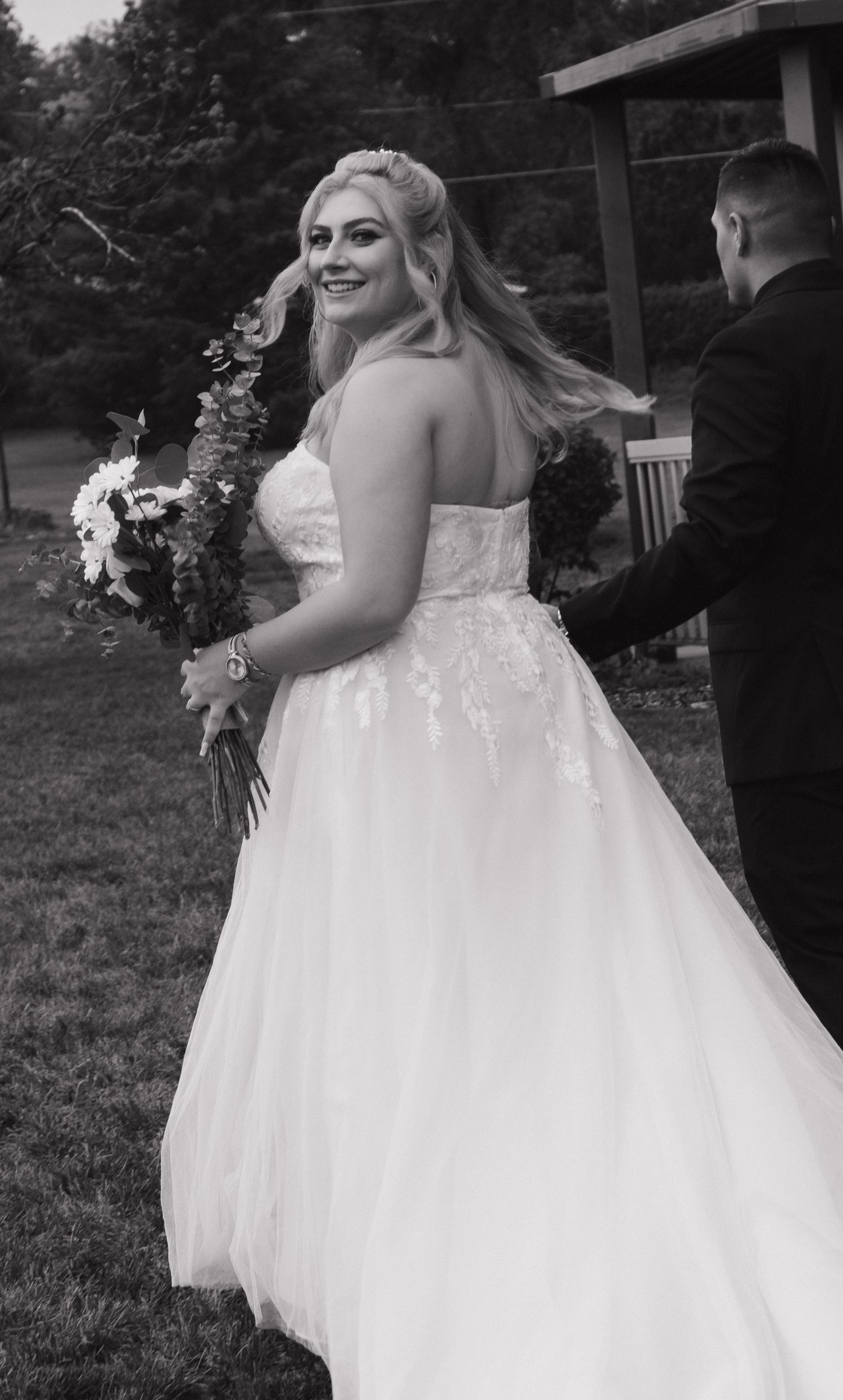 Wedding photography featuring a beautiful white ball gown and bouquet in an outdoor setting.
