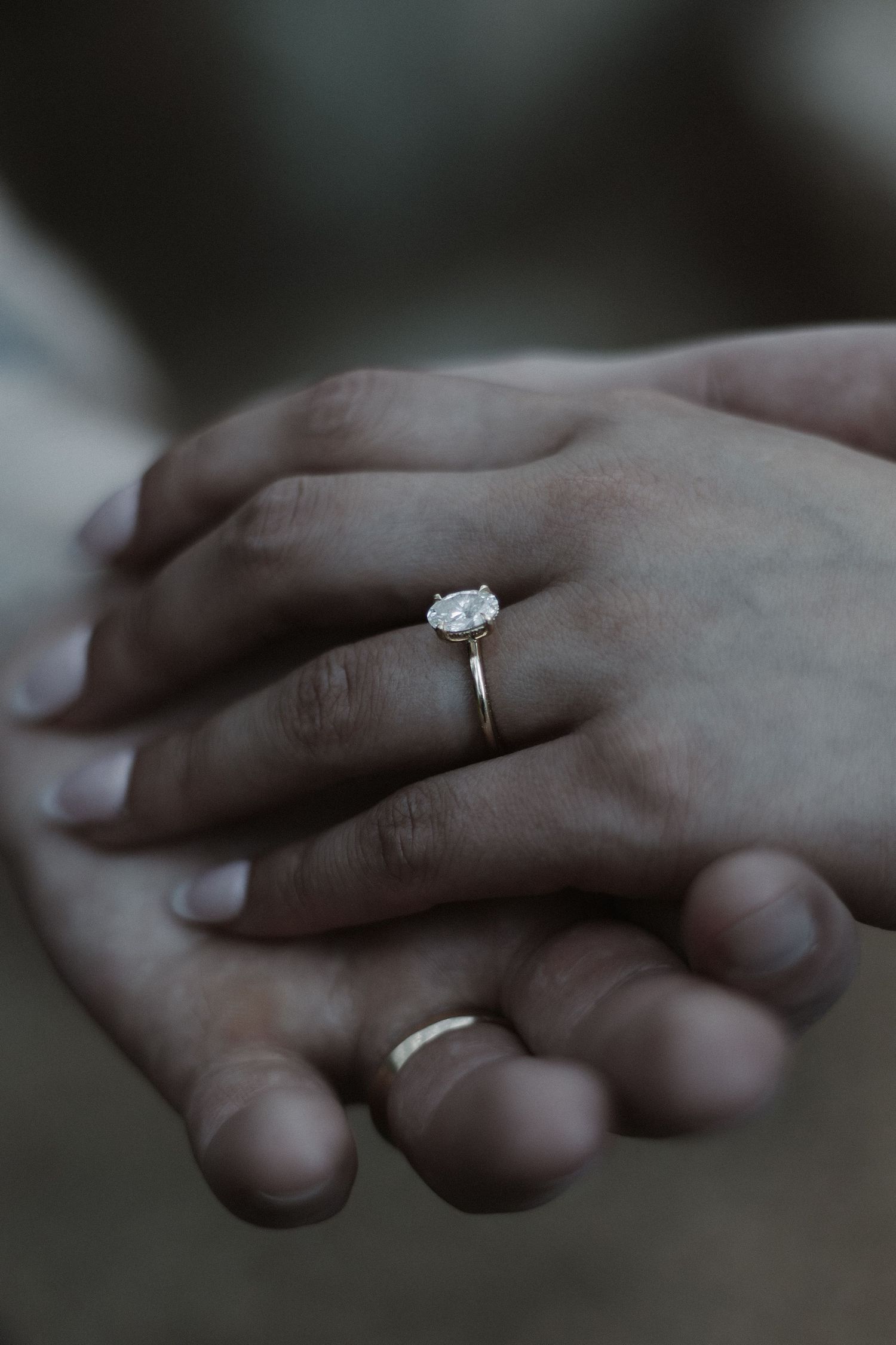 Close-up of clasped hands showing an elegant diamond engagement ring.