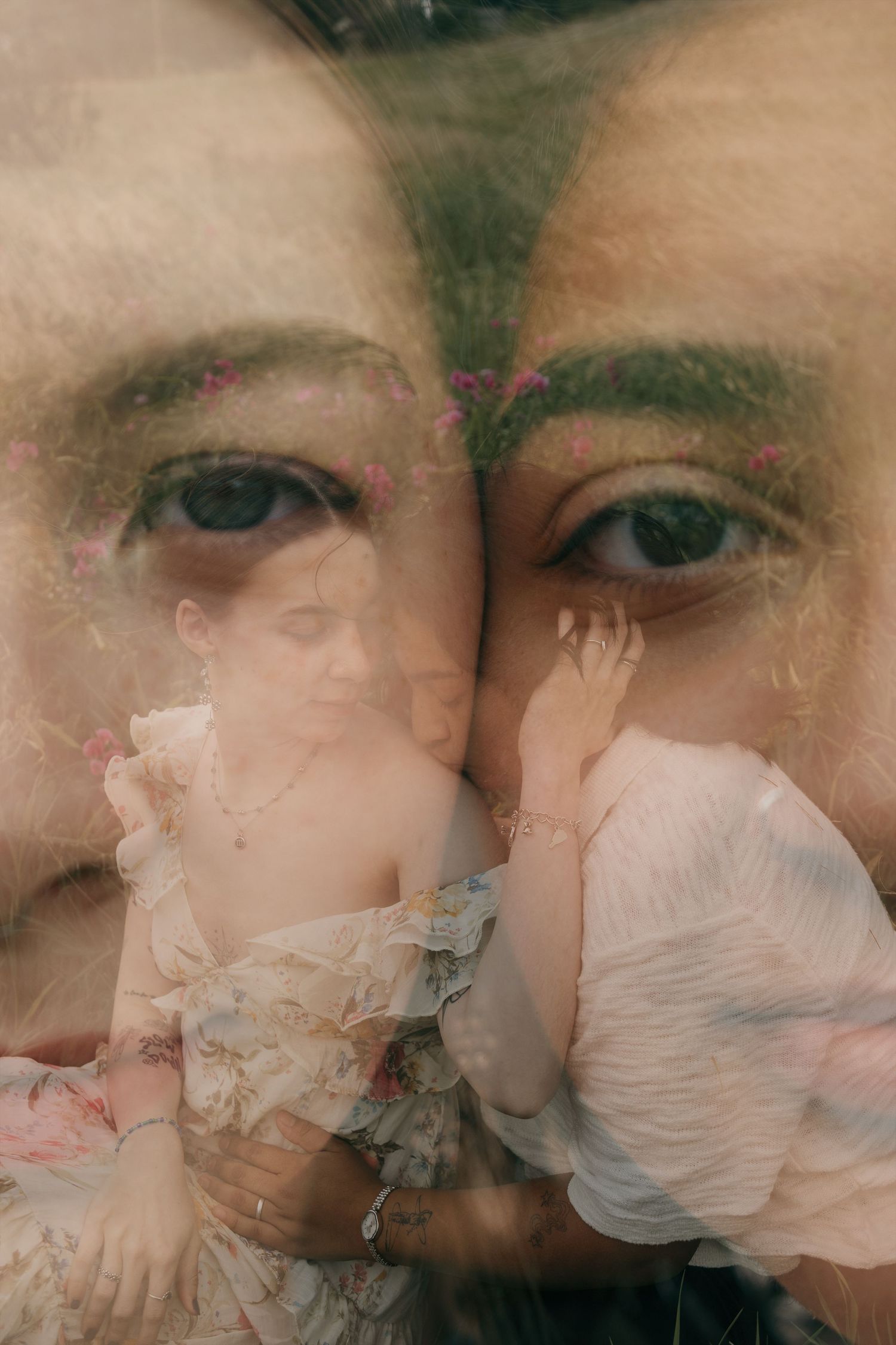 Artistic double exposure portrait blending two faces with a floral meadow landscape in soft tones.