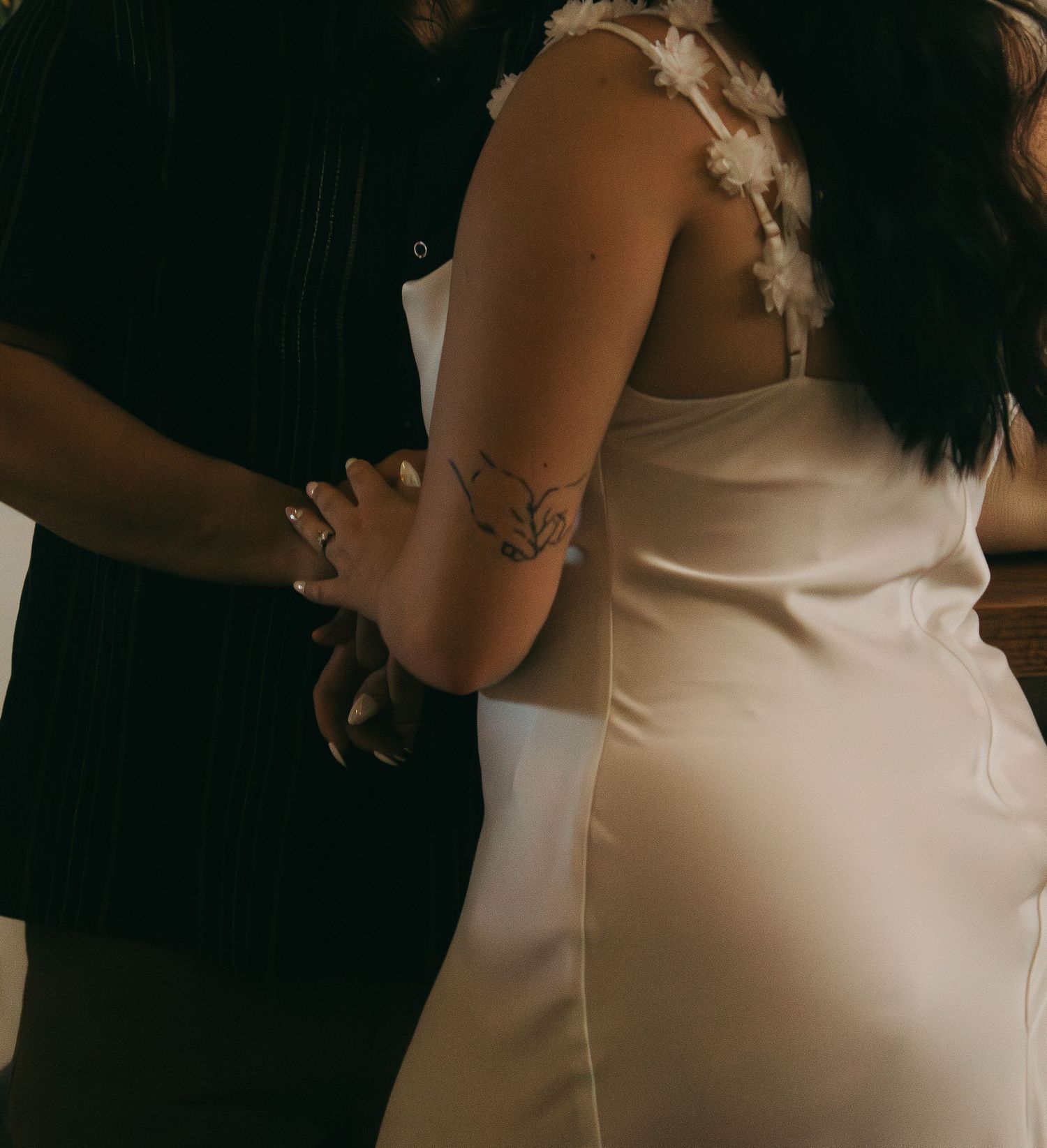 An intimate moment captured in dramatic lighting showing contrasting dark and light clothing.