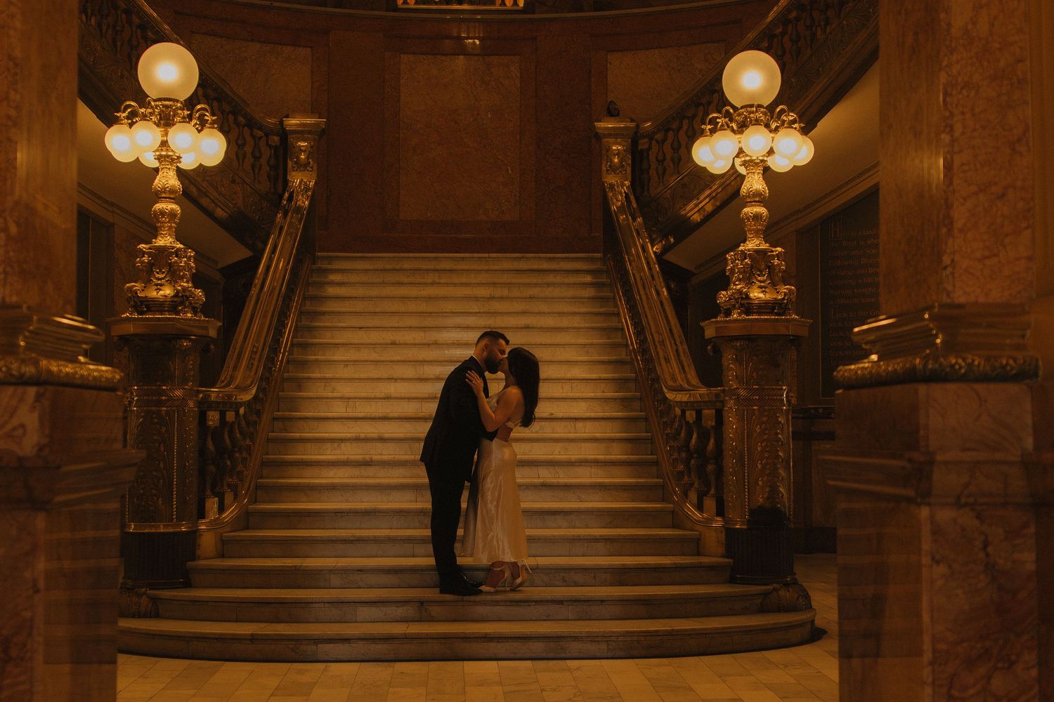 Romantic silhouette on grand staircase with vintage lighting and architecture.