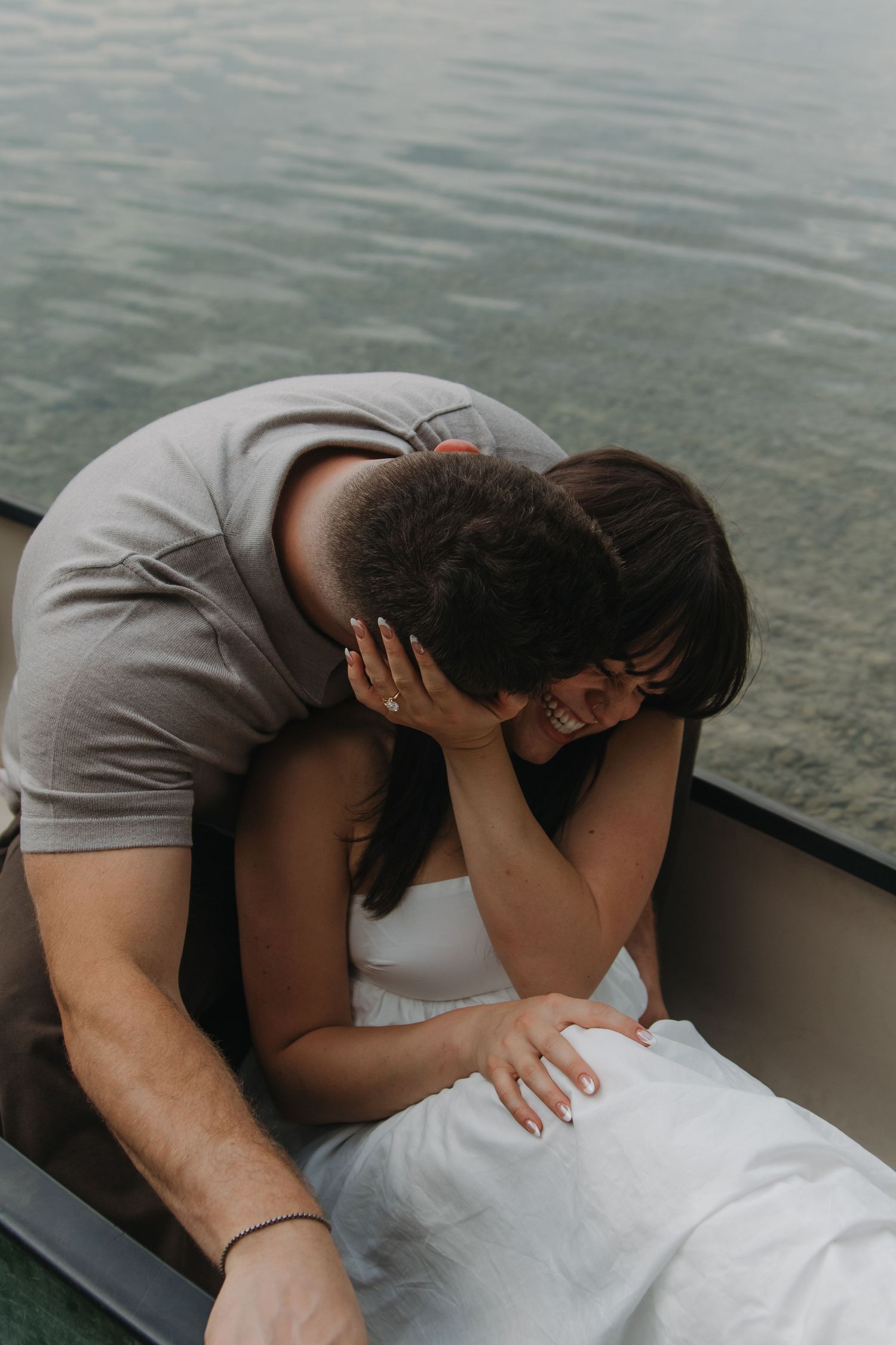 An intimate moment captured between two people sharing an embrace on a small boat at sunset.