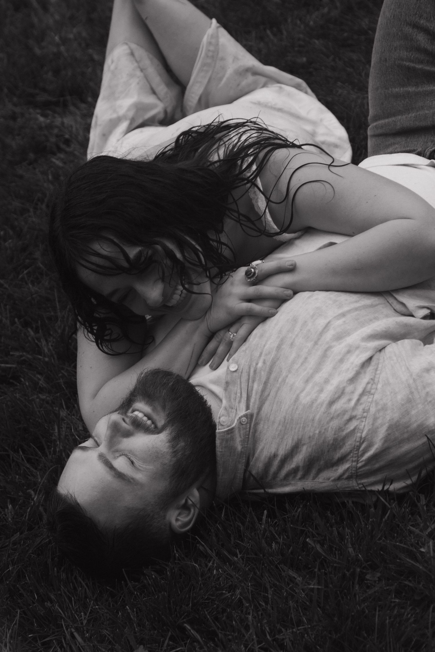 Couple lying together on grass in black and white photography showing intimate connection.