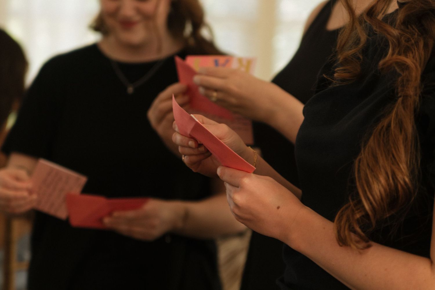 Several people holding playing cards in their hands during a casual gathering.