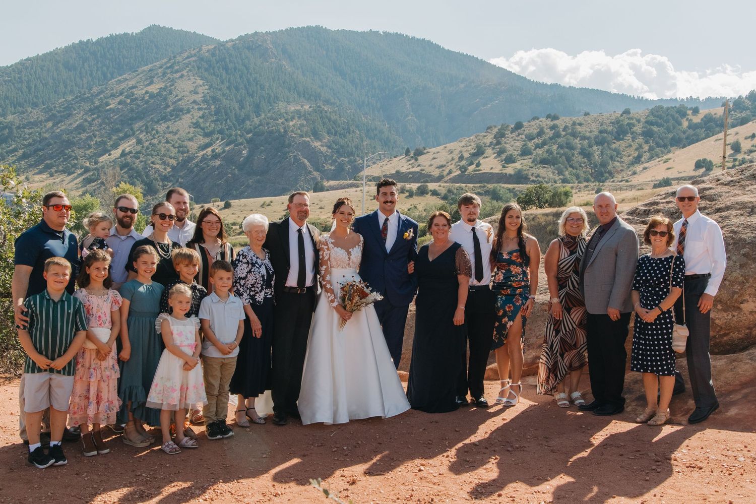 Large wedding group photo with guests lined up against a scenic mountain backdrop.