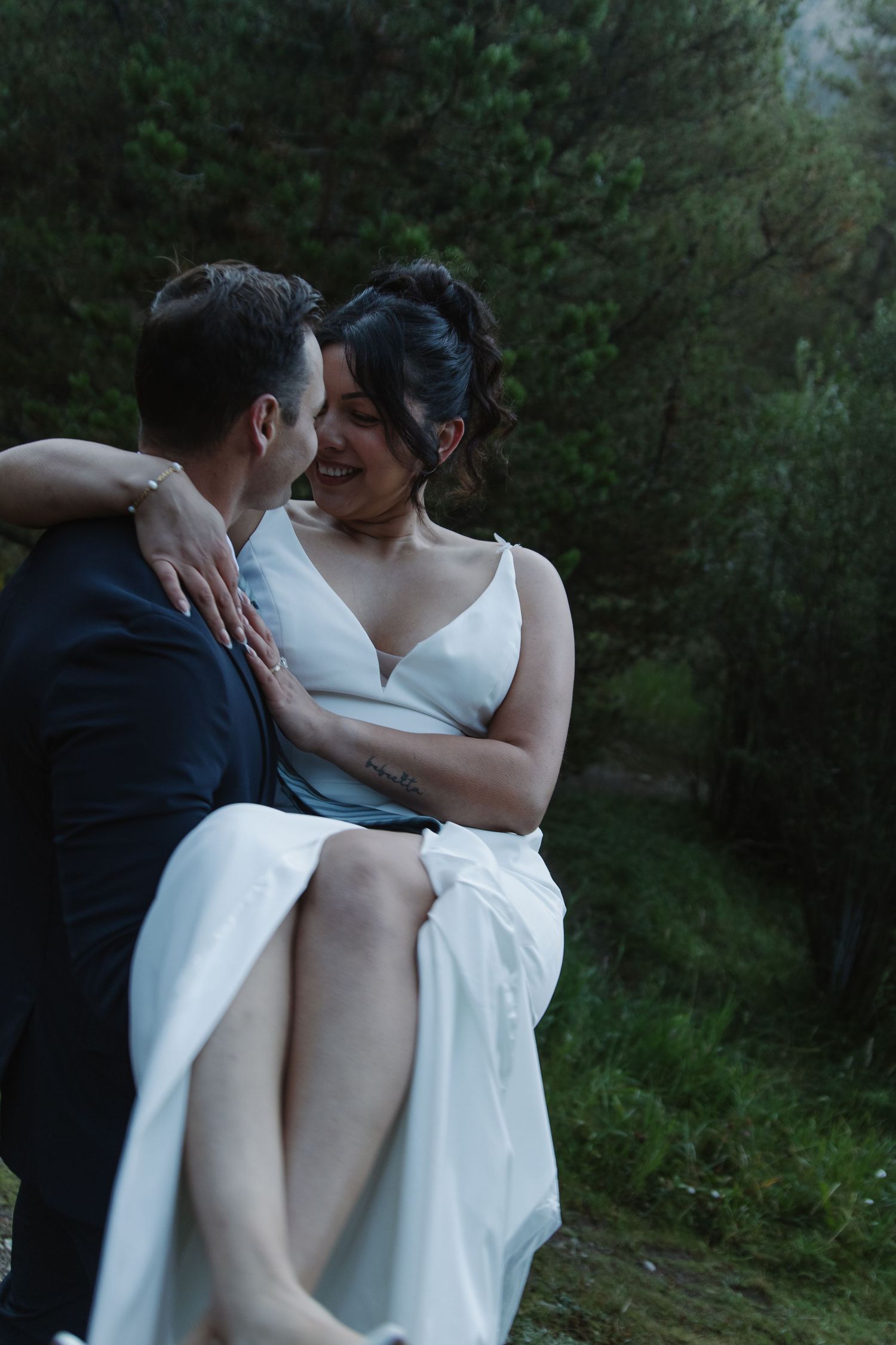 A romantic moment shared between newlyweds in an outdoor forest setting.