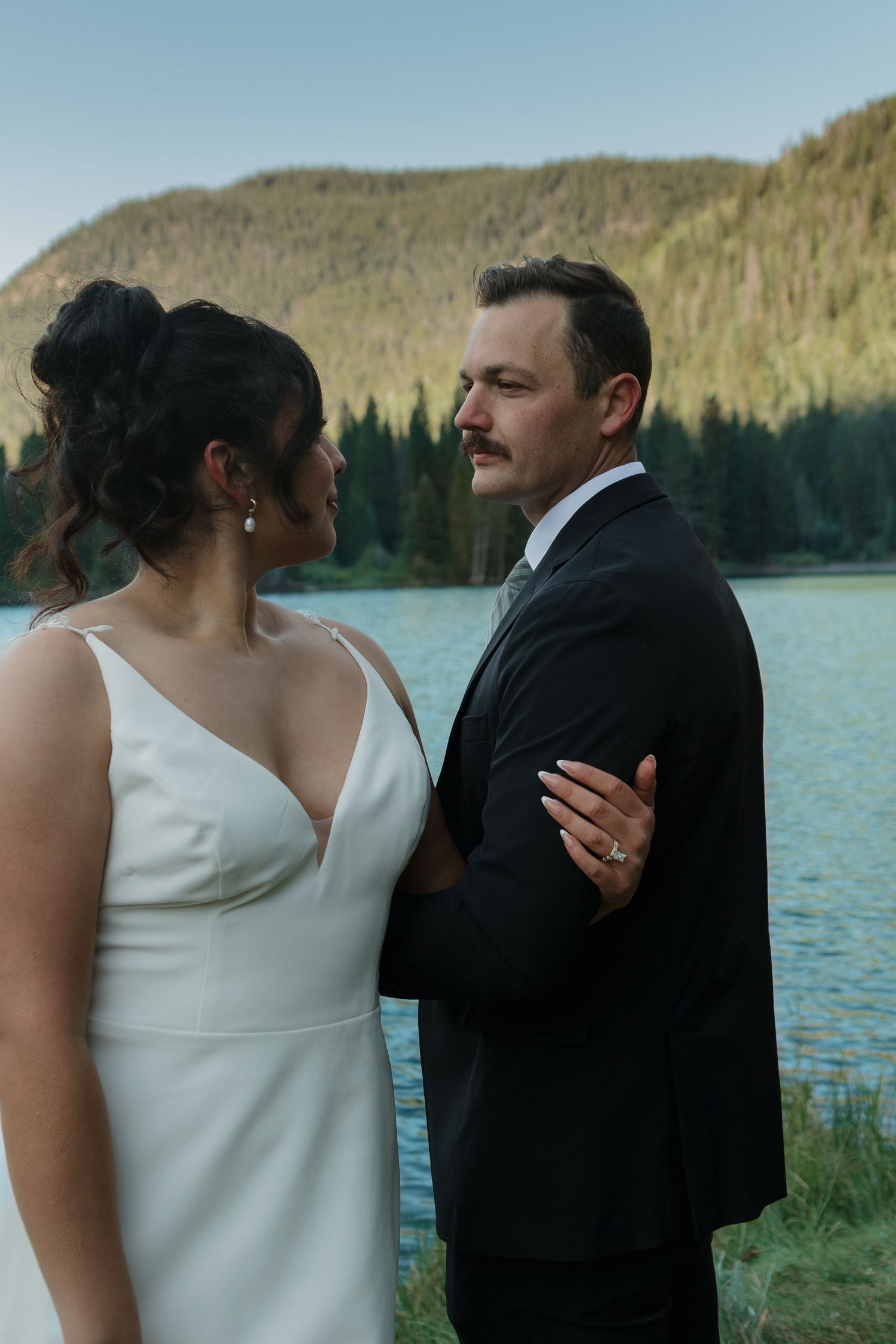 A couple shares an intimate moment during their lakeside mountain wedding.