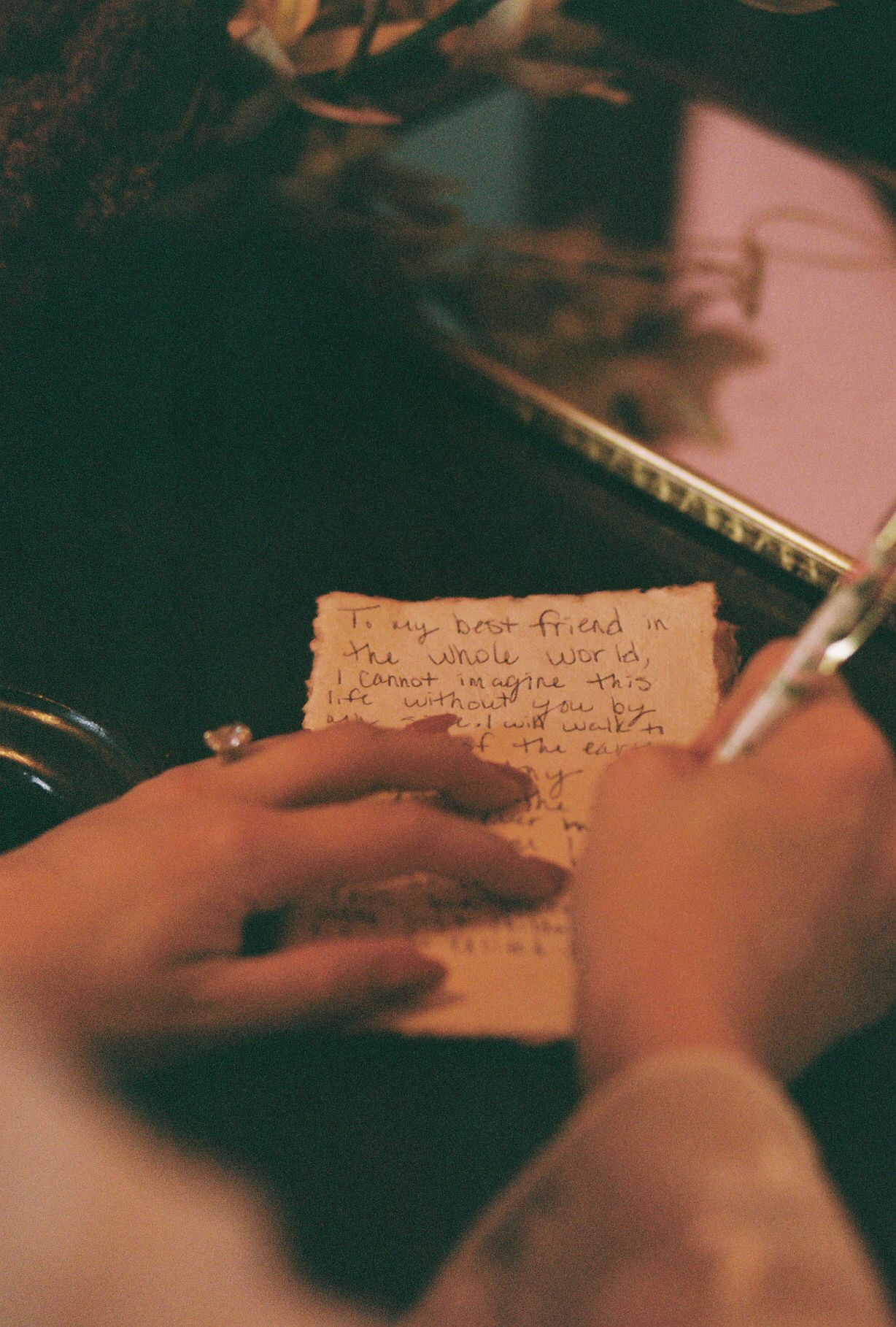 Hands writing personal notes on vintage paper in warm lighting.